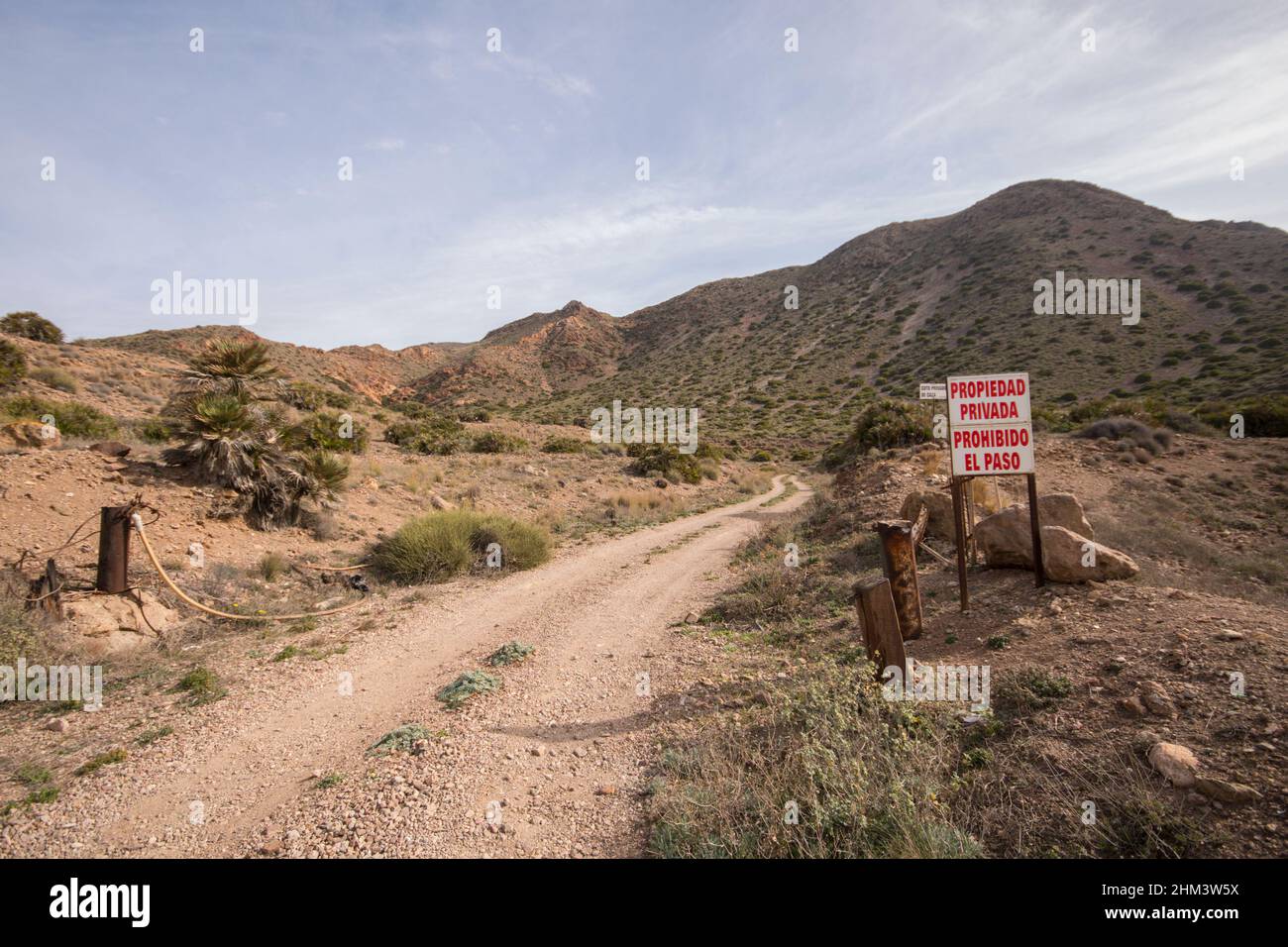 Schotterstraße, Halbwüstenlandschaft des Naturschutzgebietes Cabo de gata. Ohne Einfahrtsschild. Almeria, Andalusien, Südspanien. Stockfoto