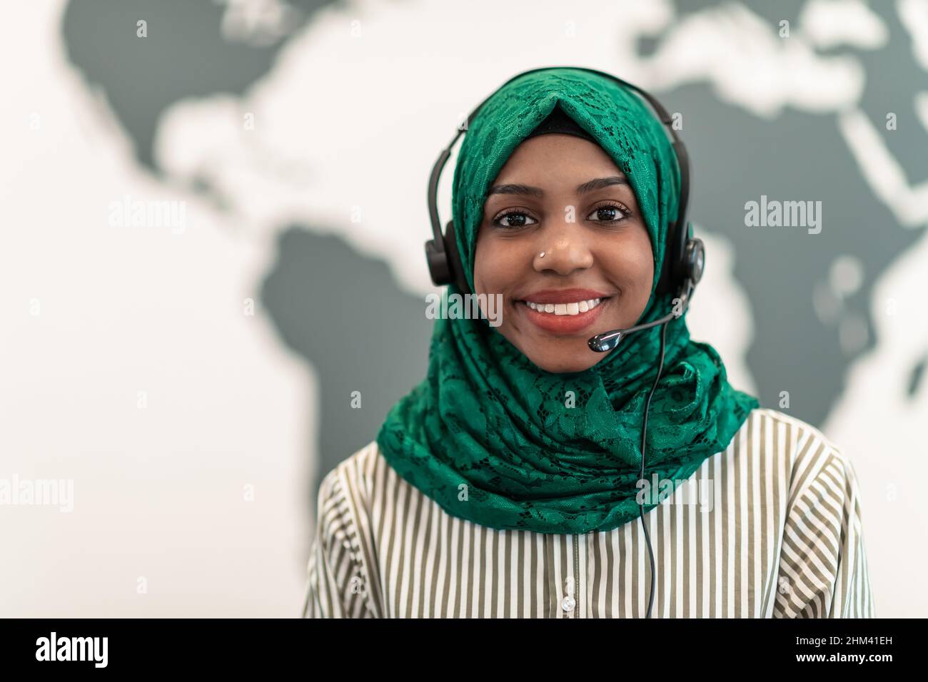 Afro-muslimische Frau mit grünem Hijab-Schal Kundenvertreterin Geschäftsfrau mit Telefon-Headset hilft und unterstützt online mit Kunden in Stockfoto