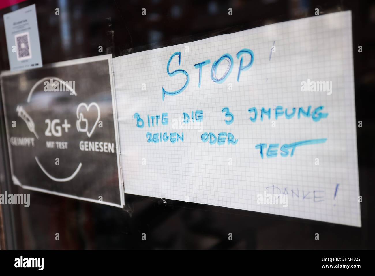 07. Februar 2022, Hamburg: Ein Schild mit der Aufschrift „Stop! Bitte zeigen Sie 3 Impfungen oder Tests an - Vielen Dank!' Und „geimpft, 2G+ mit Test, erholt“ hängt neben der Eingangstür eines Cafés im Stadtteil Hamburg-Veddel. Foto: Christian Charisius/dpa Stockfoto
