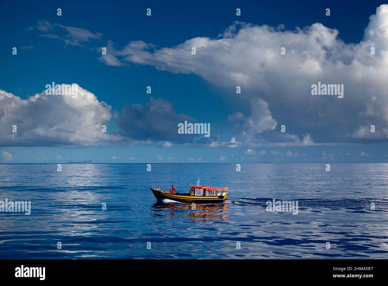 Ein kleines Fischerboot, das auf den Seychellen zwischen den Inseln Mahe und La Digue perfekte, glasige Bedingungen steuert. Stockfoto
