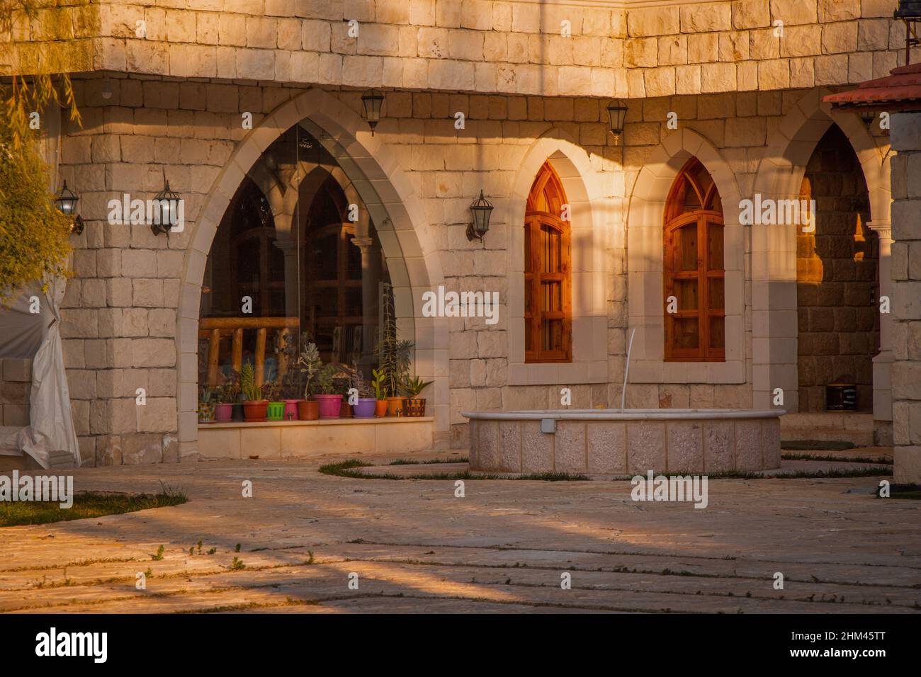 Steinhaus mit Holzfenstern trifft das Sonnenlicht, mit Pflanzen. Haus im alten Stil, mit einer Kamera als Landschaft gedreht. Stockfoto