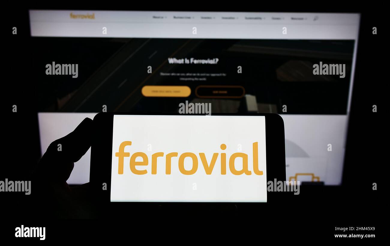 Person, die das Smartphone mit dem Logo der spanischen Baufirma Ferrovial S.A. auf dem Bildschirm vor der Website hält. Konzentrieren Sie sich auf die Telefonanzeige. Stockfoto