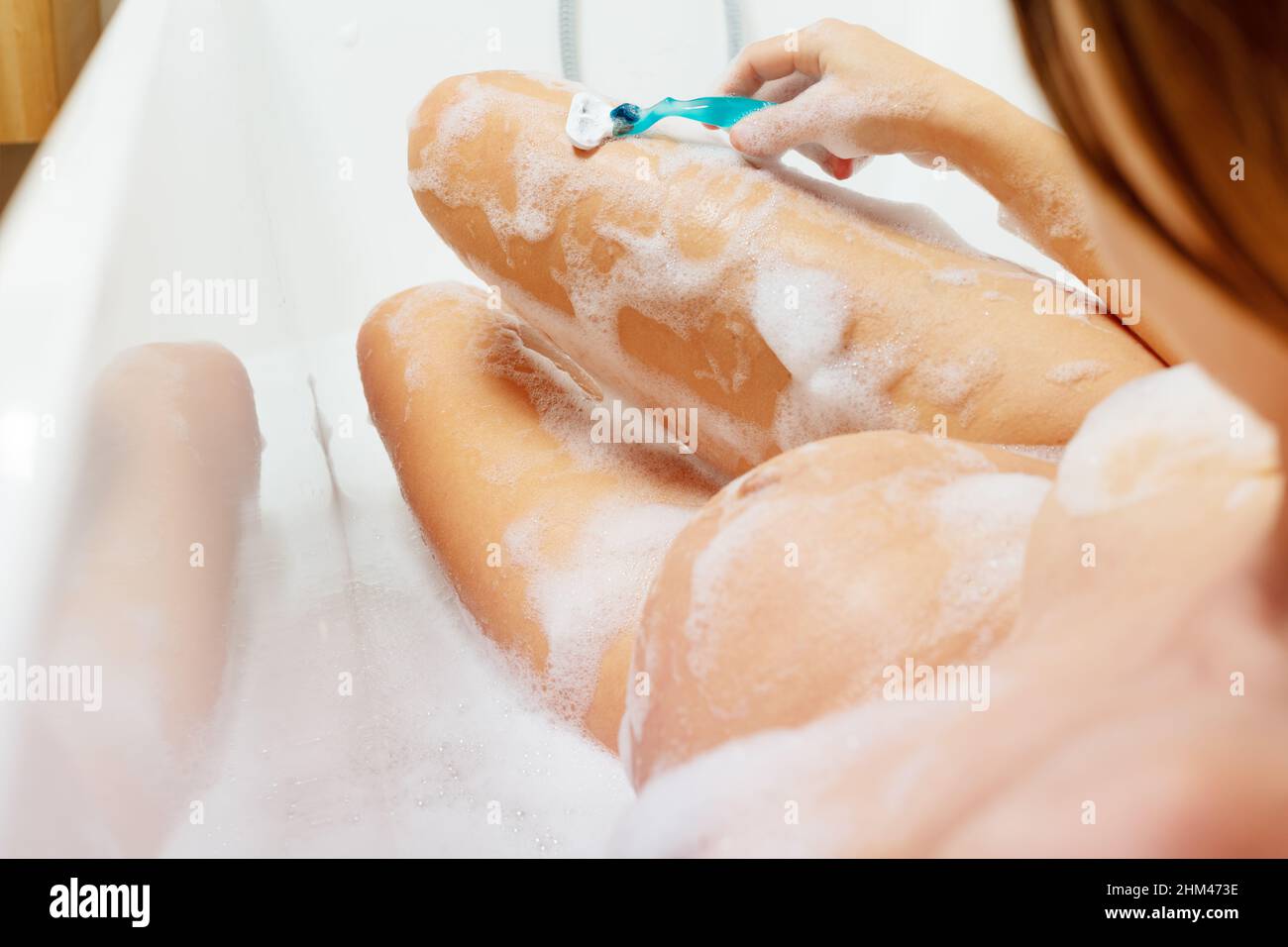 Schwanger Frau rasieren Bein entspannt im Bad mit Schaum Stockfoto