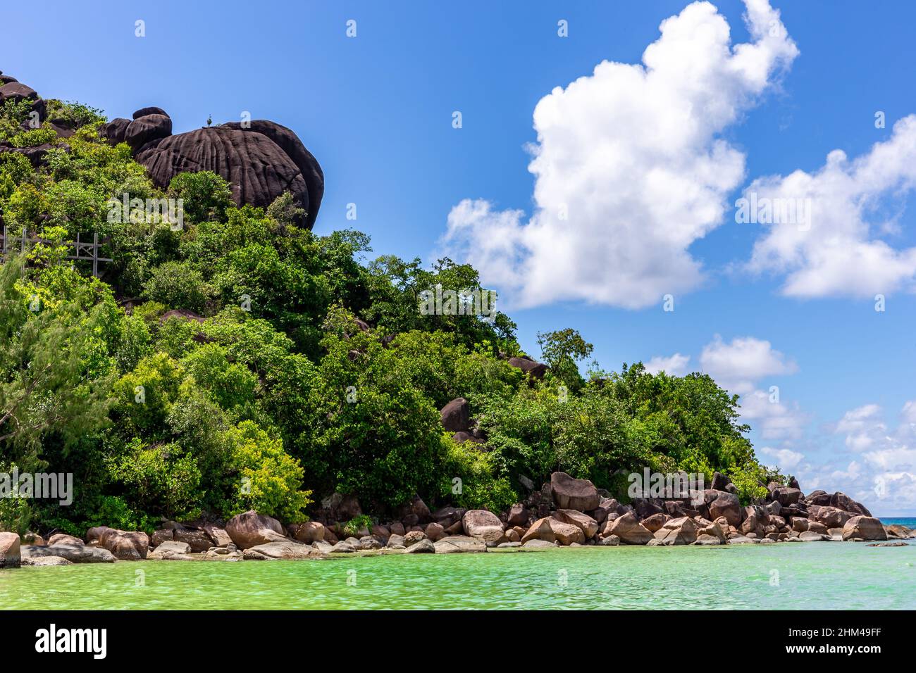 Küste der Insel Praslin, Seychellen, mit großen Granitfelsen, üppiger tropischer Vegetation und azurblauem Wasser im Indischen Ozean. Stockfoto