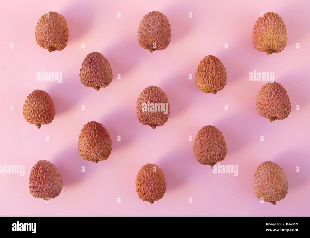 Litschi-Früchte-Muster auf dem rosa Hintergrund. Litchi chinensis Stockfoto