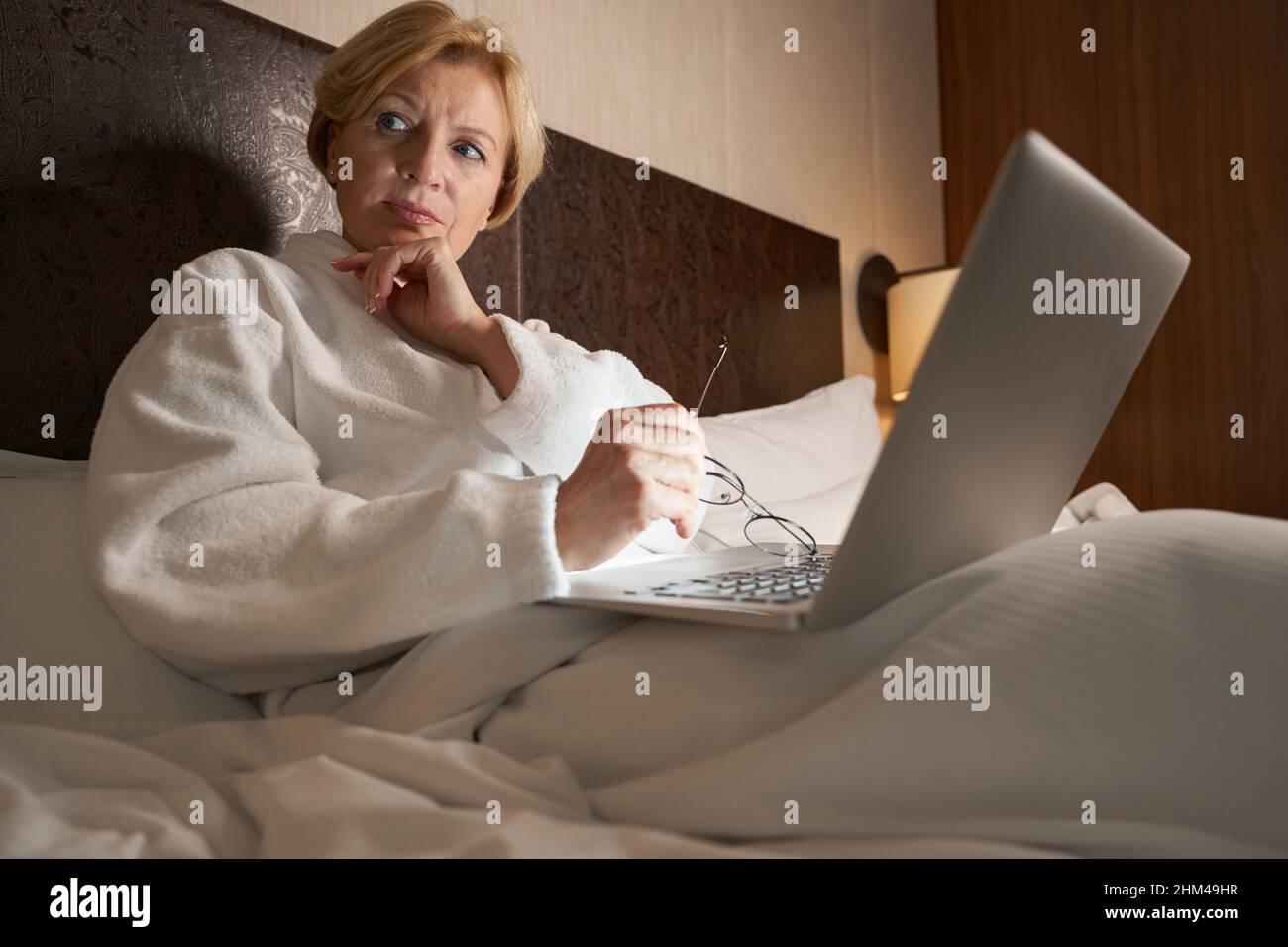 Besorgt blonde Frau mit ihrem Laptop im Bett Stockfoto