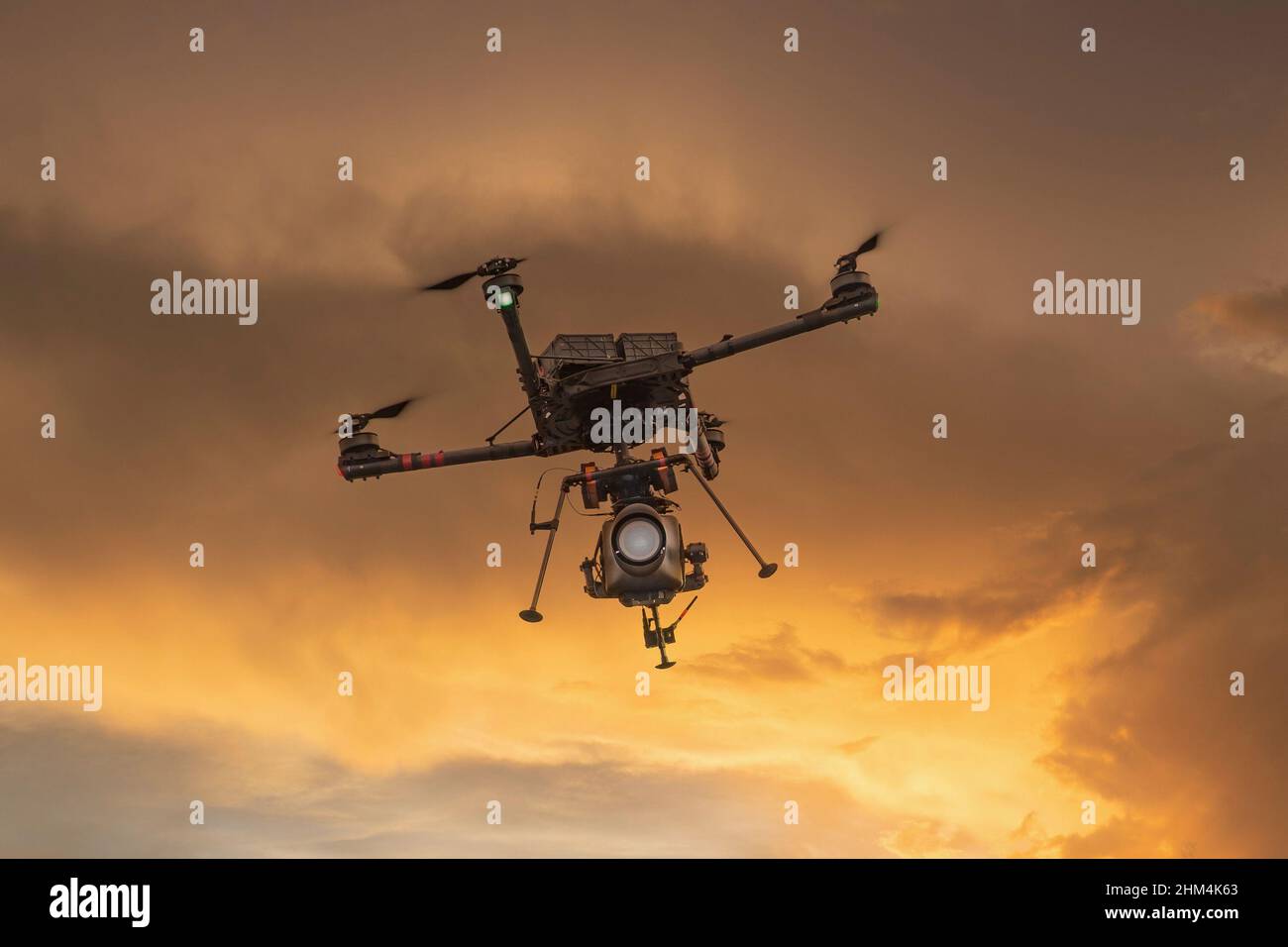 Professionelle Video- und Kamera-Drohne, die in einem goldenen Sonnenuntergangshimmel fliegt. Stockfoto