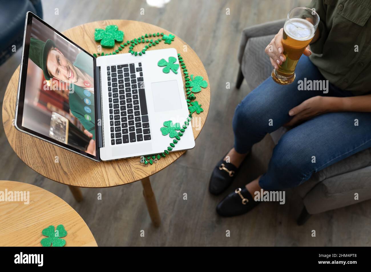 Eine mittlere Frau, die ein Bierglas hält, während sie an einer Bar eine Videokonferenz auf einem Laptop veranstaltet Stockfoto