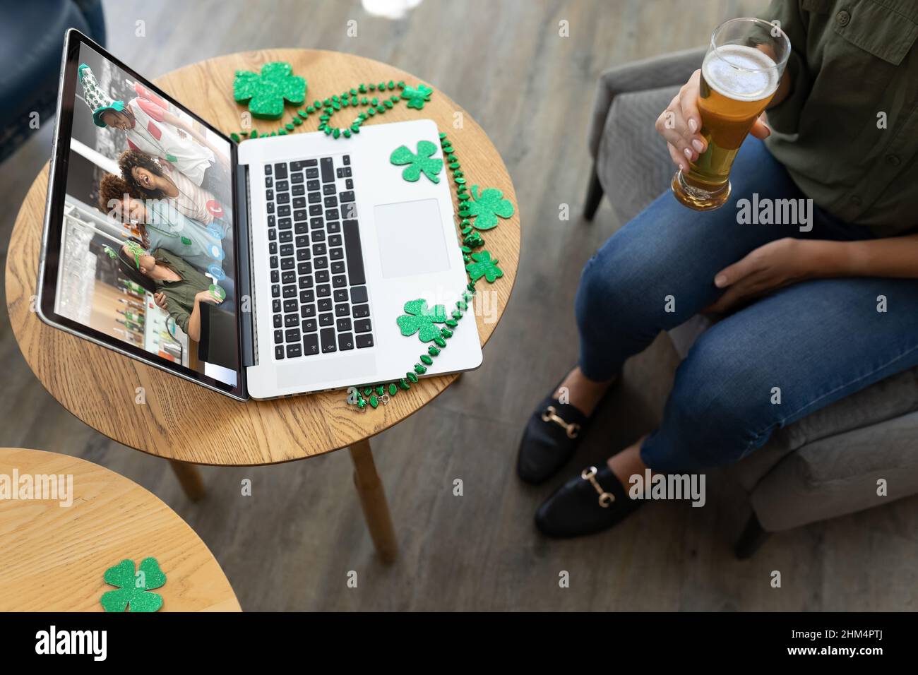 Eine mittlere Frau, die ein Bierglas hält, während sie an einer Bar eine Videokonferenz auf einem Laptop veranstaltet Stockfoto