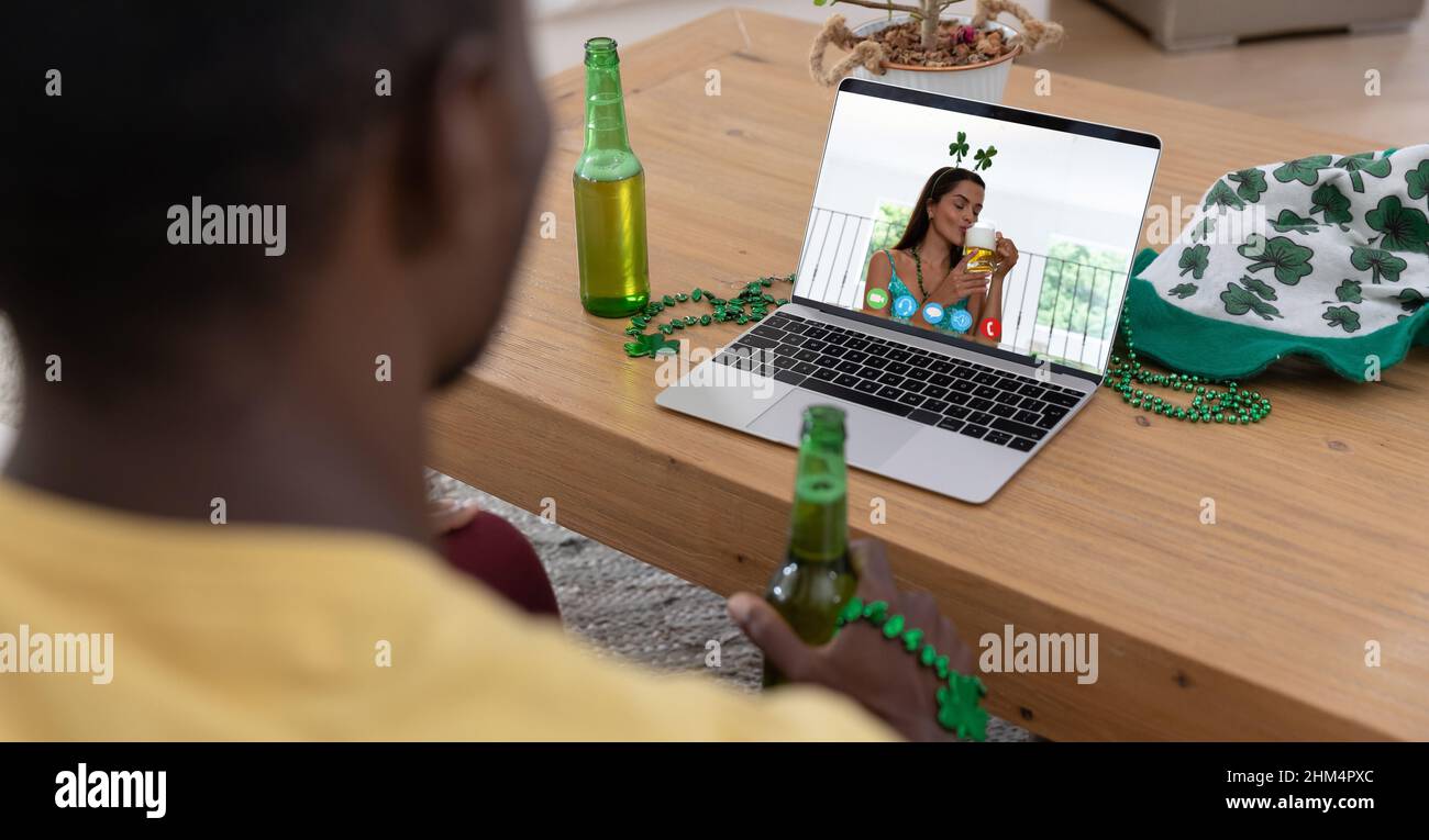 afroamerikanischer Mann, der ein Bier in der Hand hält und zu Hause einen Videoanruf auf dem Laptop führt Stockfoto