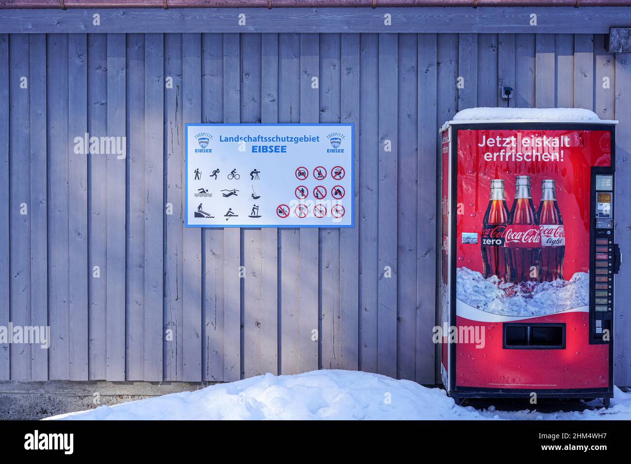 Erfrischen Sie sich jetzt eiskalt, der Werbeslogan auf einem Coca Cola-Automaten am Eibsee, Zugspitze. Schnee liegt vor dem Automaten. Stockfoto