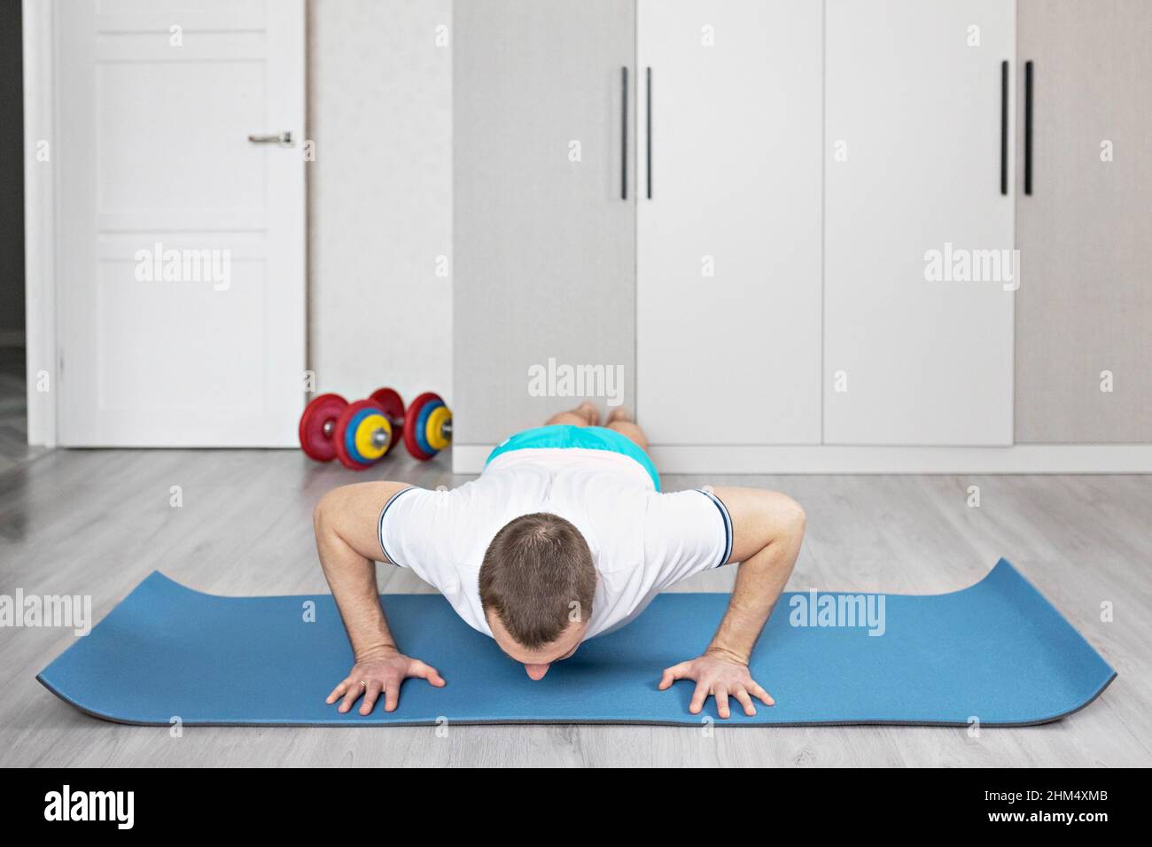 Ein starker, gesunder Mann mit Muskeln, der zu Hause in der Plank-Position trainiert. Fitness zu Hause Stockfoto