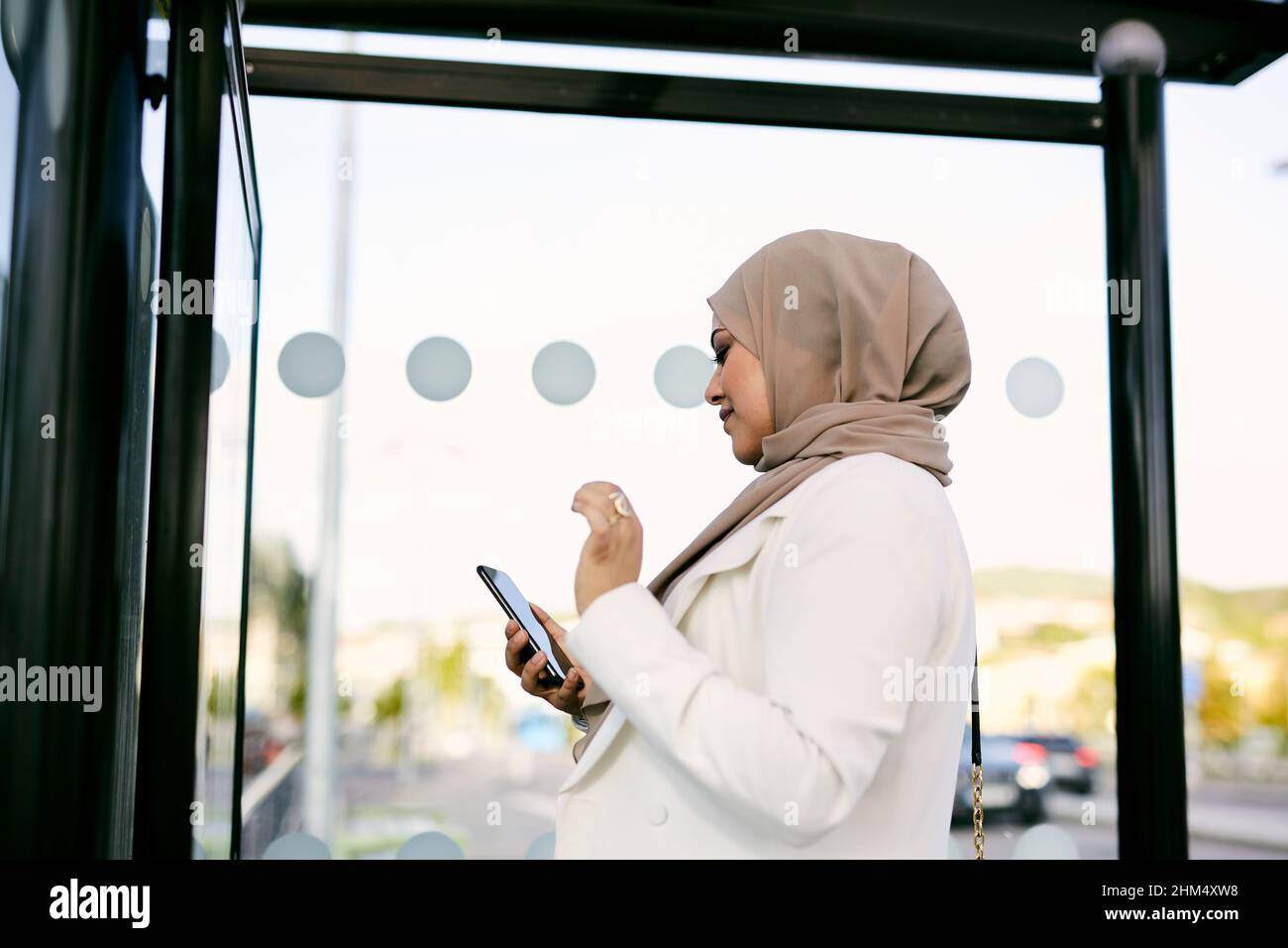 Frau benutzt Handy an der Bushaltestelle Stockfoto
