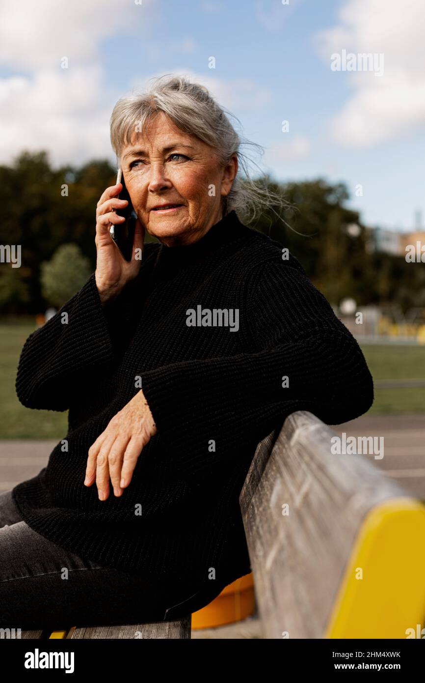 Ältere Frau, die im Park ein Mobiltelefon benutzt Stockfoto