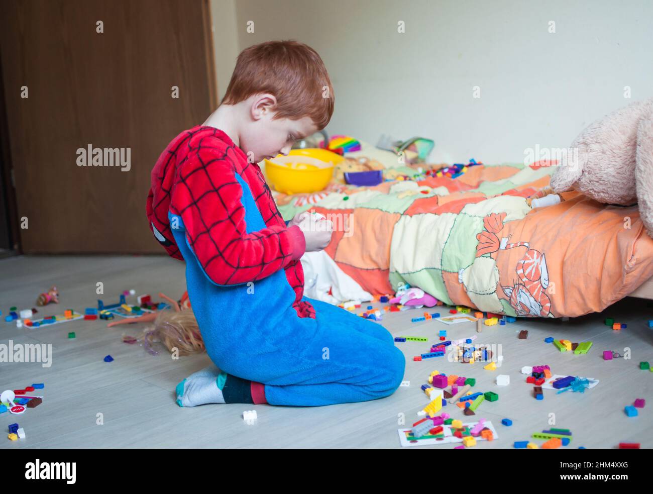 Das Kind spielt allein in seinem Schlafzimmer mit farbigen Mauergliedern Stockfoto