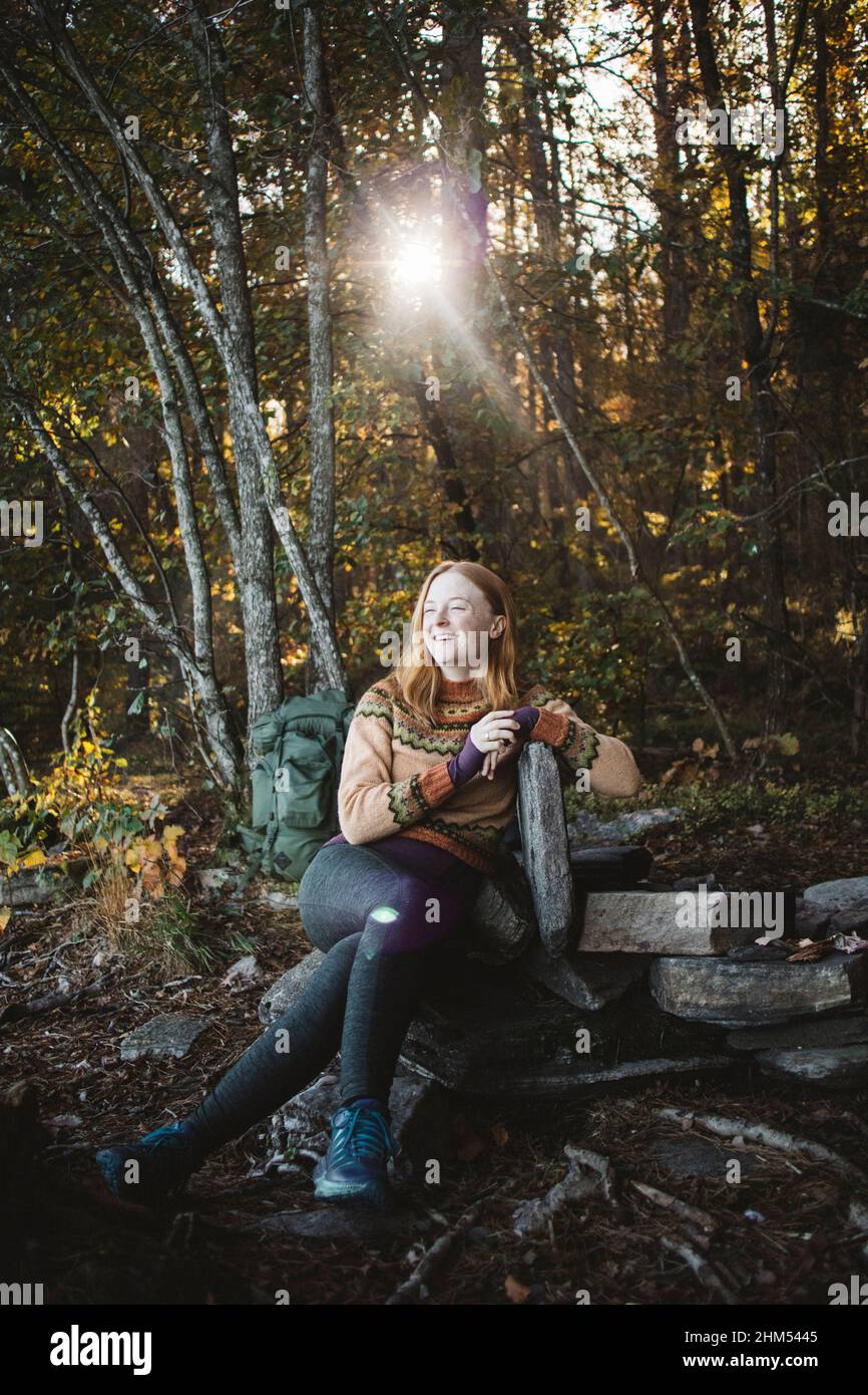 Lächelnde Wandererin, die im Wald sitzt Stockfoto