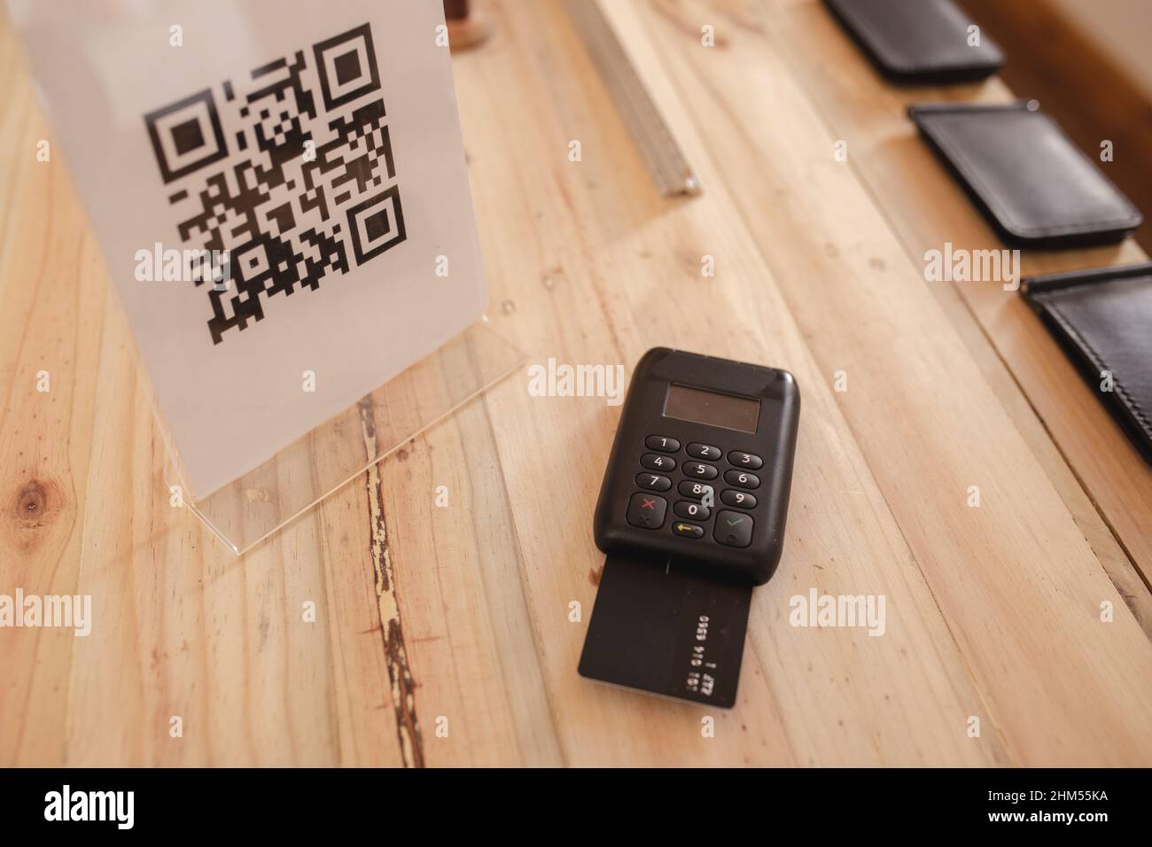 High-Angle-Ansicht von qr-Code und Kreditkartenleser Maschine auf Holztisch im Lederlager Stockfoto