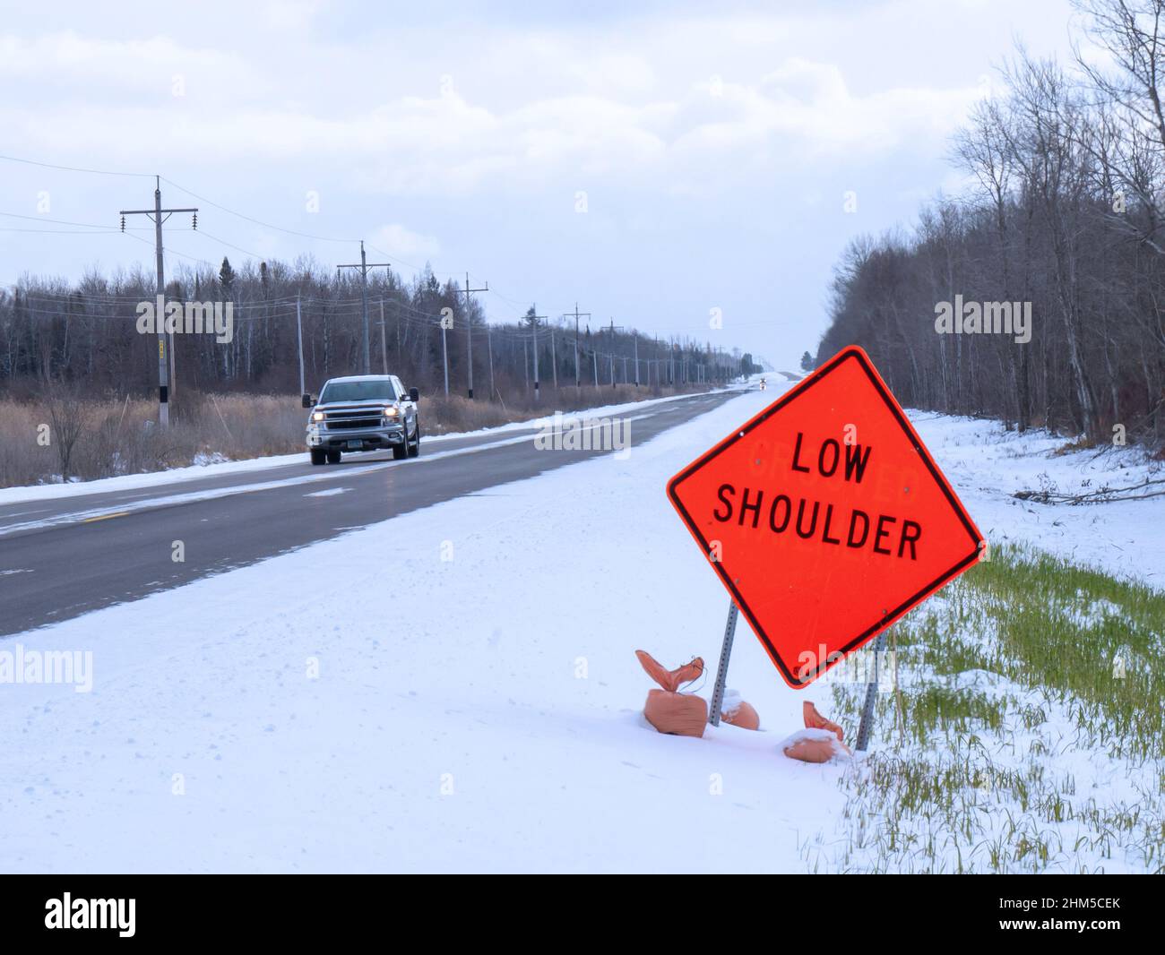 Orange Low Shoulder Schild entlang der Landstraße im Winter Stockfoto