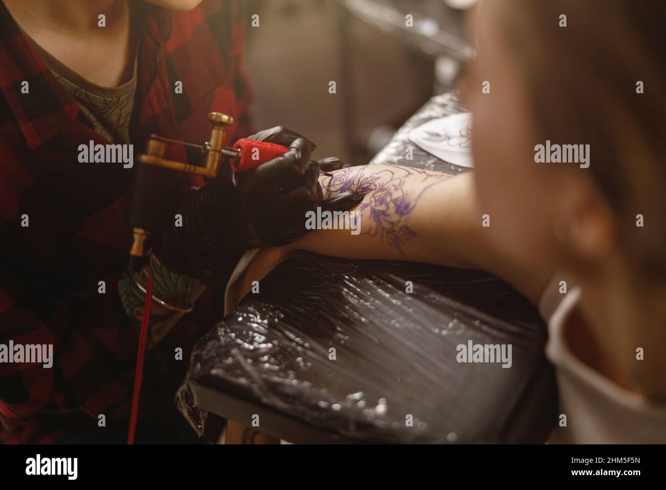 Nahaufnahme Foto von Tattoo Master Hände in Handschuhen vorsichtig halten Tattoo Maschine Stockfoto