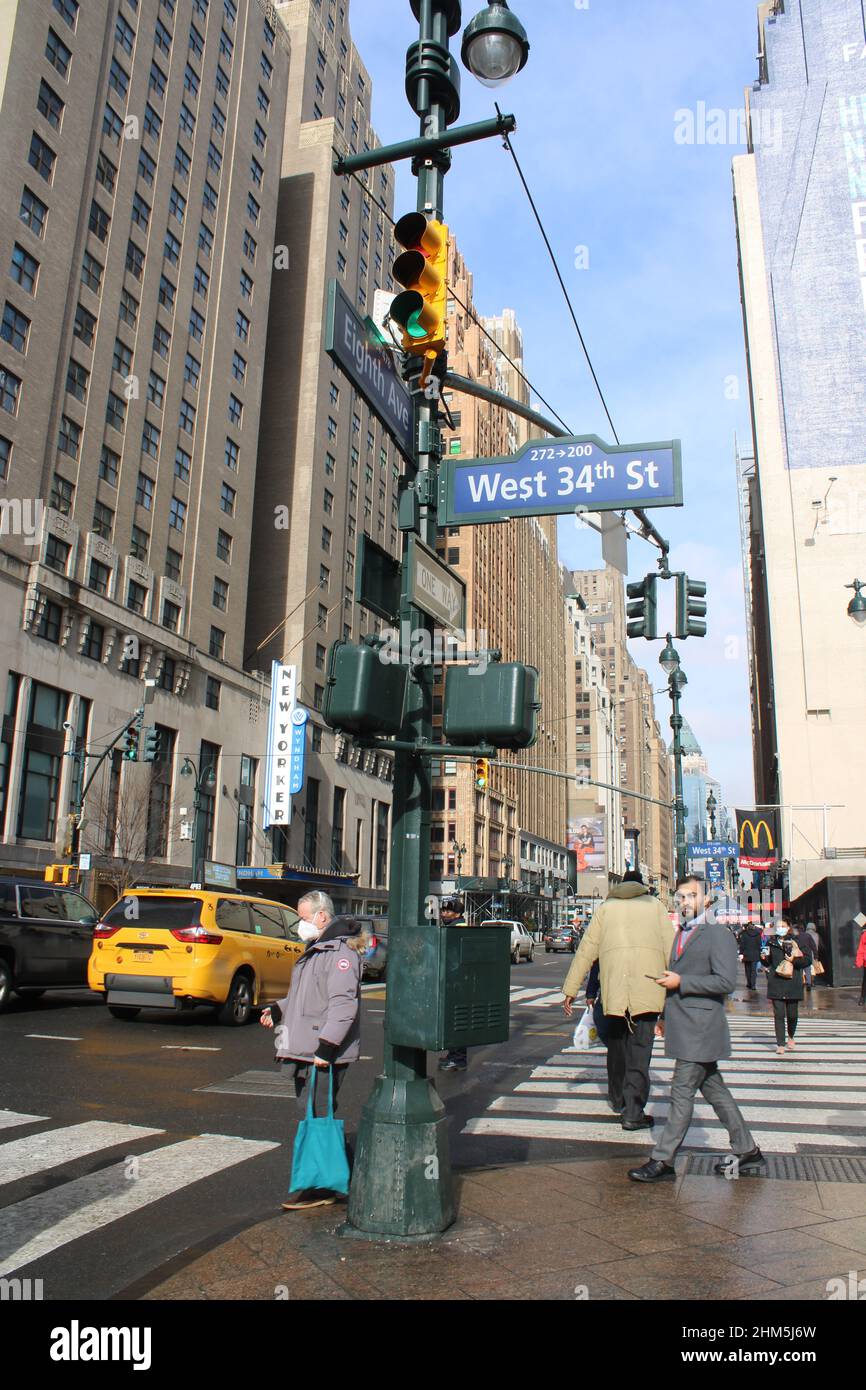 Menschen, die in Midtown Manhattan entlang der 34th Street und 8th Avenue gehen Stockfoto