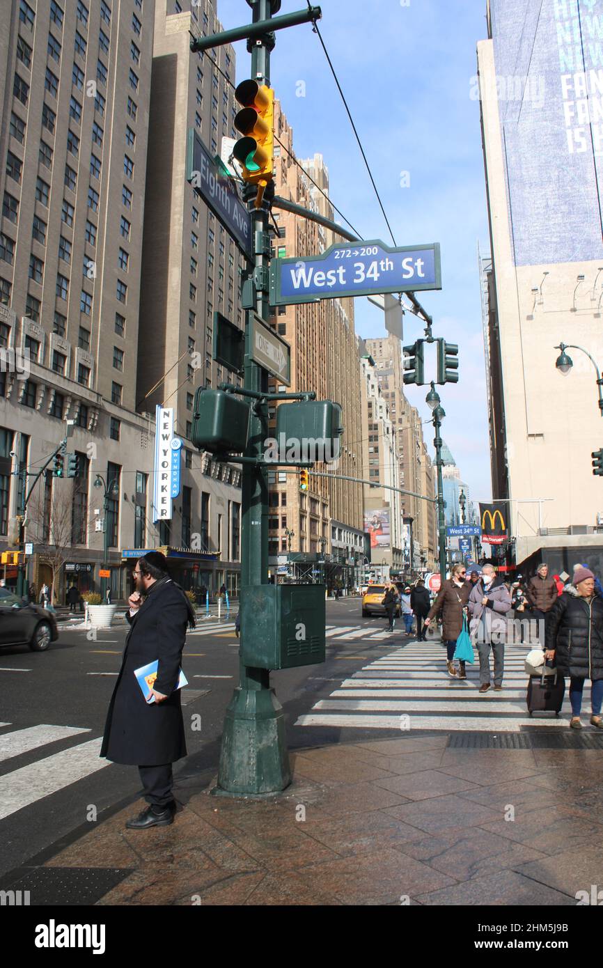 Menschen, die in Midtown Manhattan entlang der 34th Street und 8th Avenue gehen Stockfoto
