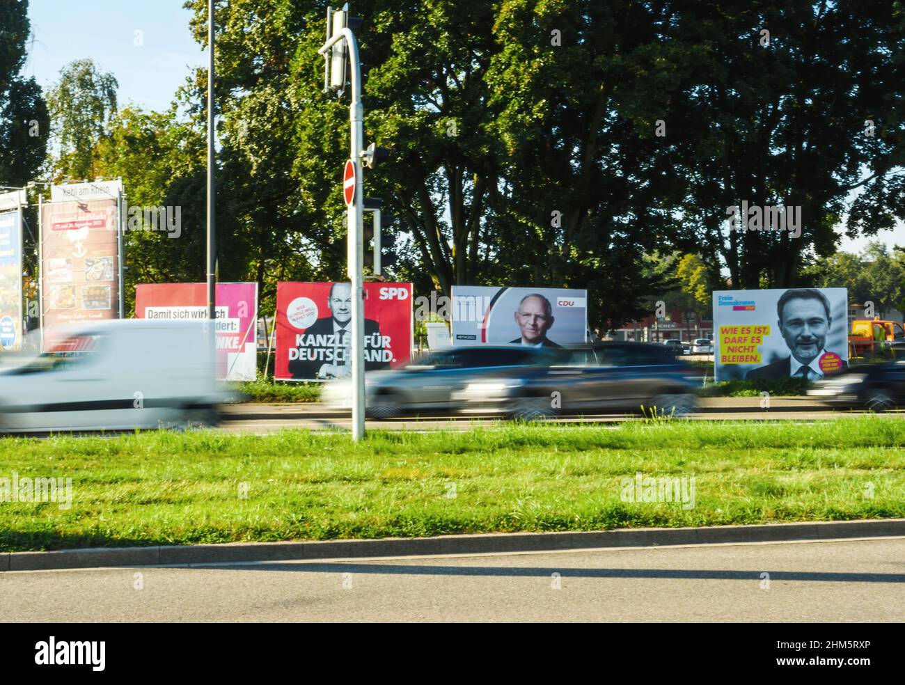 Kehl, 24. Sep 2021: Autos fahren schnell City Street mit Wahlplakaten mit den Kanzlerkandidaten der SPD mit Olaf Scholz, CDU mit Armin Laschet und Bundnis 90 die Grunen mit Annalena Baerbock. Deutsche Bürger sind zur Wahl eines neuen Bundestages aufgerufen. Stockfoto