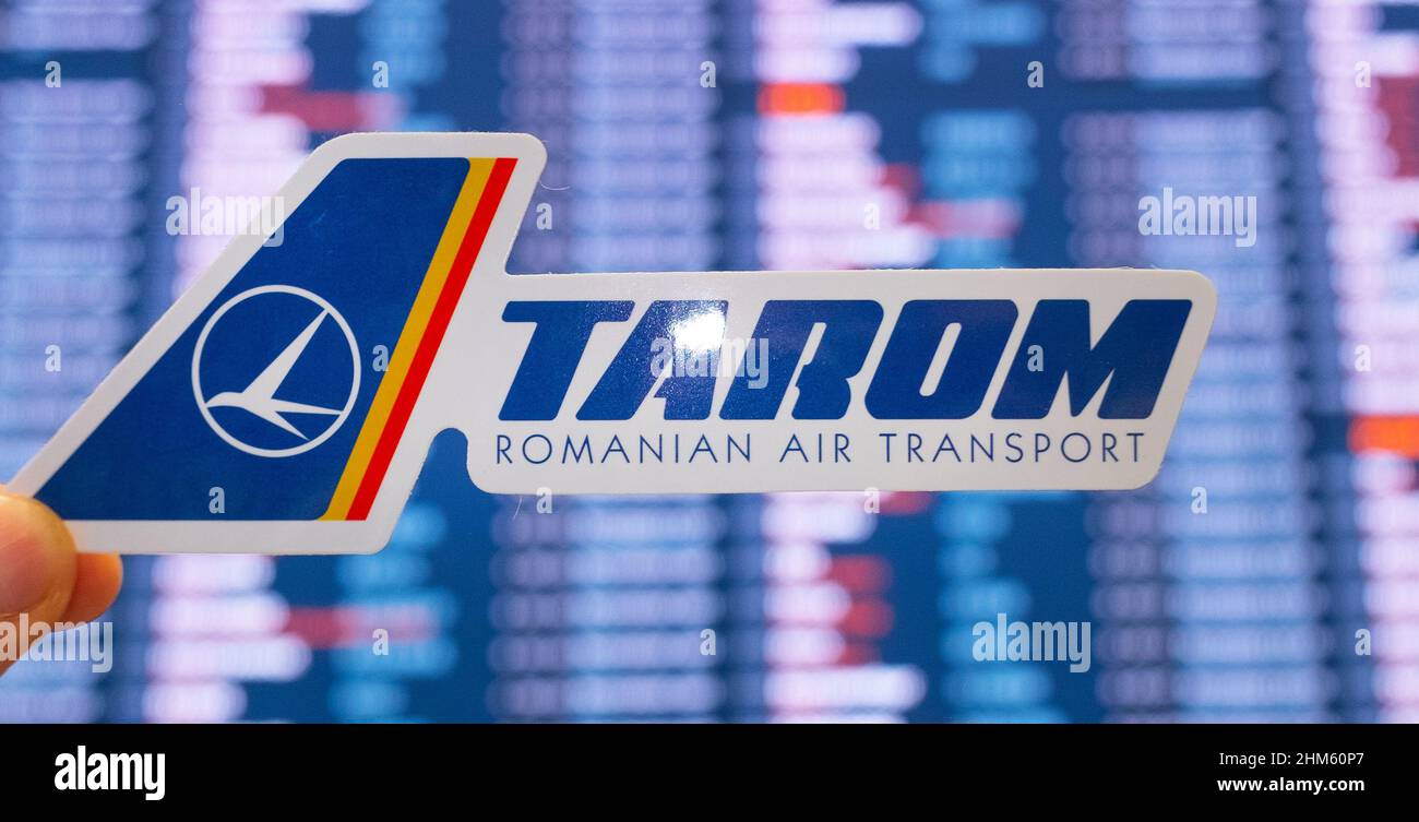 11. Dezember 2021, Bukarest, Rumänien. Das Emblem der Fluggesellschaft TAROM vor dem Hintergrund einer elektronischen Tafel mit einem Flugplan auf der int Stockfoto