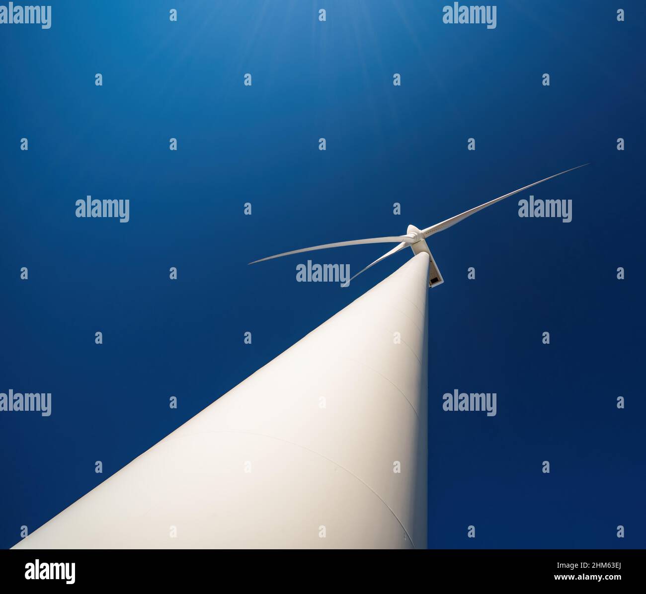 Dreiblätterige Windturbine vor tiefblauem Himmel, Blick nach oben mit dramatischer Perspektive Stockfoto