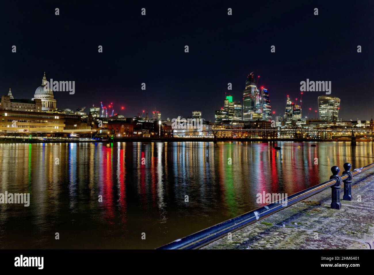 Farbenfrohe Reflexionen in der Themse von den Lichtern des Londoner Finanzzentrums mit seinen verschiedenen Wolkenkratzern, die die Nacht erleuchten Stockfoto