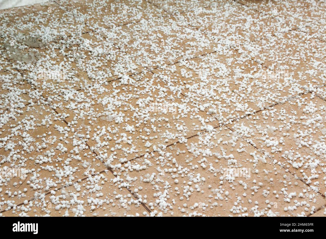 Die Schneekörner auf den Fliesen des Balkons im Winter Stockfoto