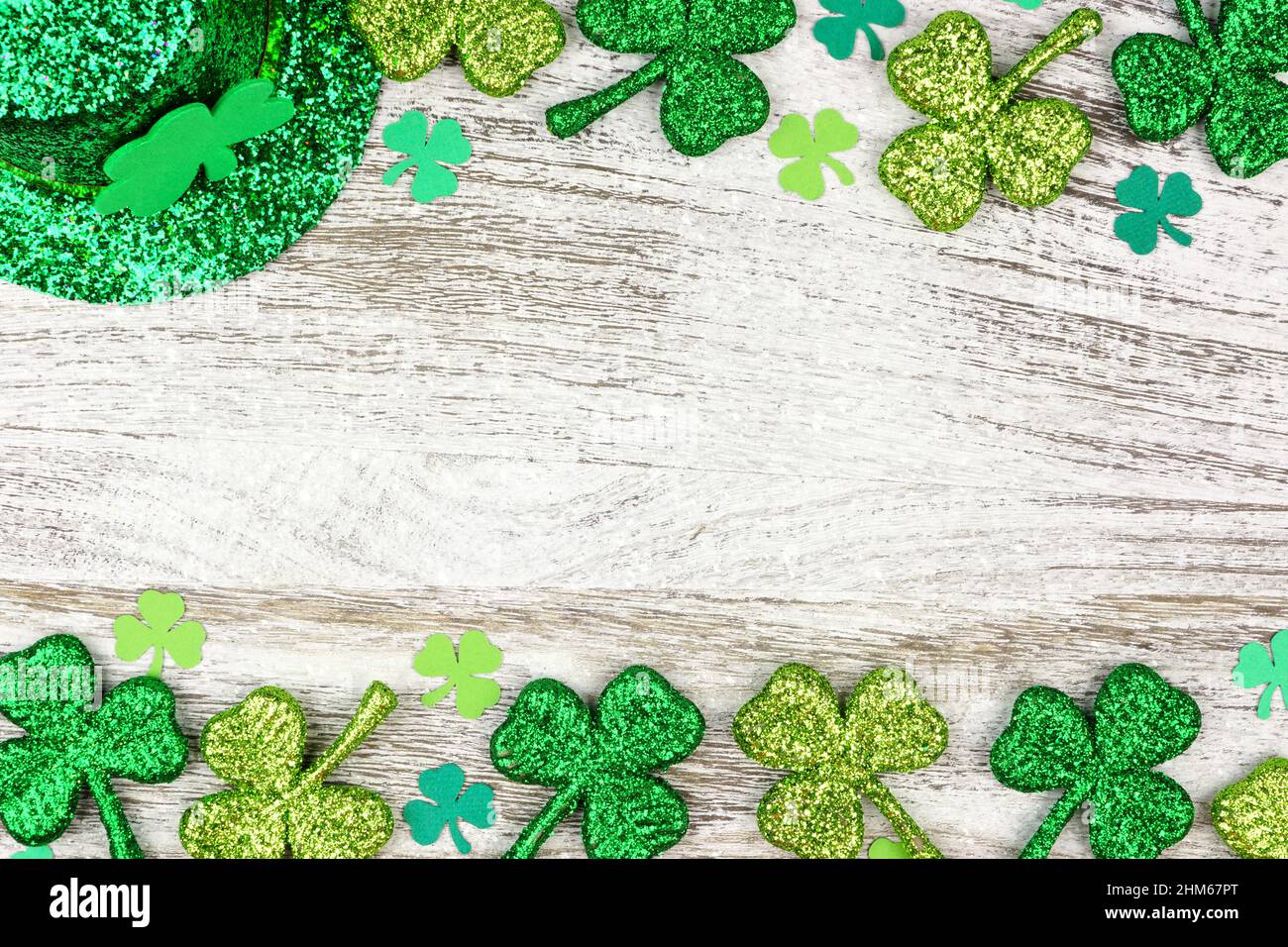 St. Patricks Day doppelte Grenze von Kleeblättern mit Kobold Hut über einem rustikalen weißen Holz Hintergrund Stockfoto