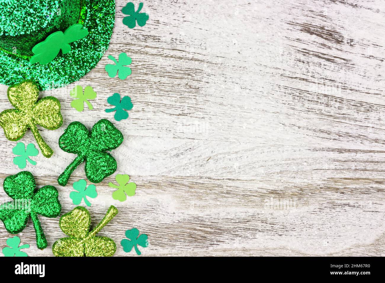 St. Patricks Day Seitenrand von Kleeblättern mit Kobold Hut über einem rustikalen weißen Holz Hintergrund Stockfoto
