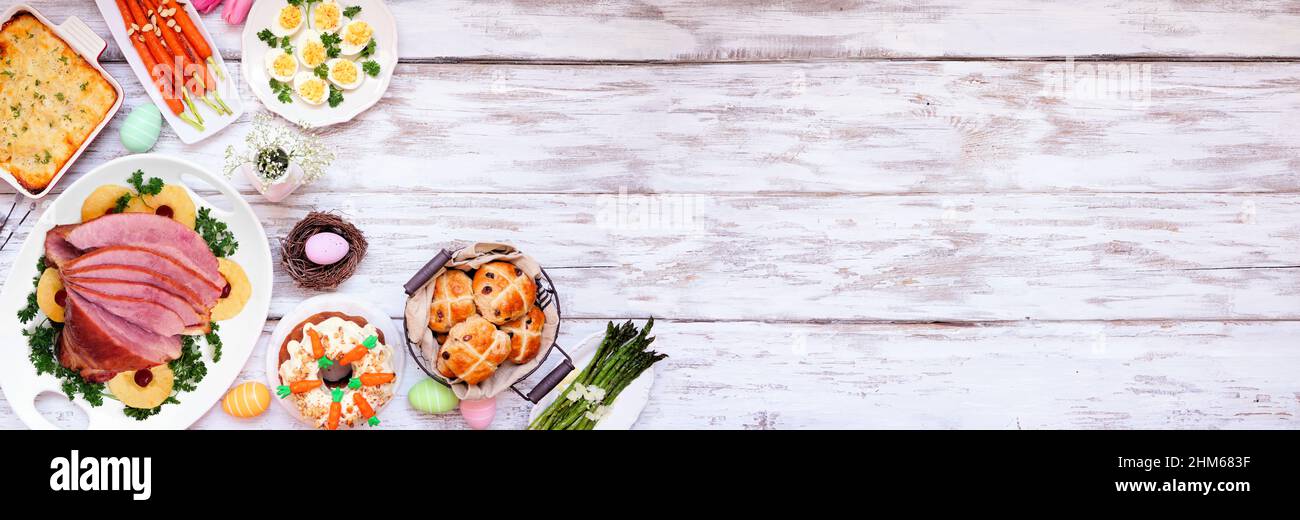 Traditionelles Abendessen mit Osterschinken. Eckrand der Deckenansicht auf einem weißen Holzbanner mit Kopierfläche. Schinken, Jakobskartoffeln, Gemüse, Ei Stockfoto