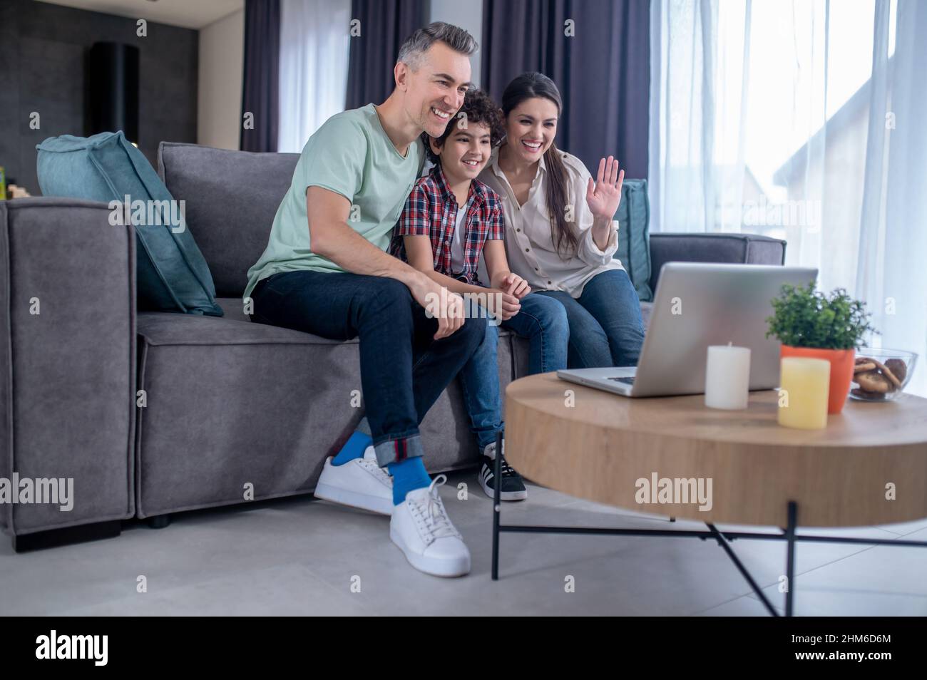 Mann, Frau und Junge blicken auf den Laptop-Bildschirm Stockfoto