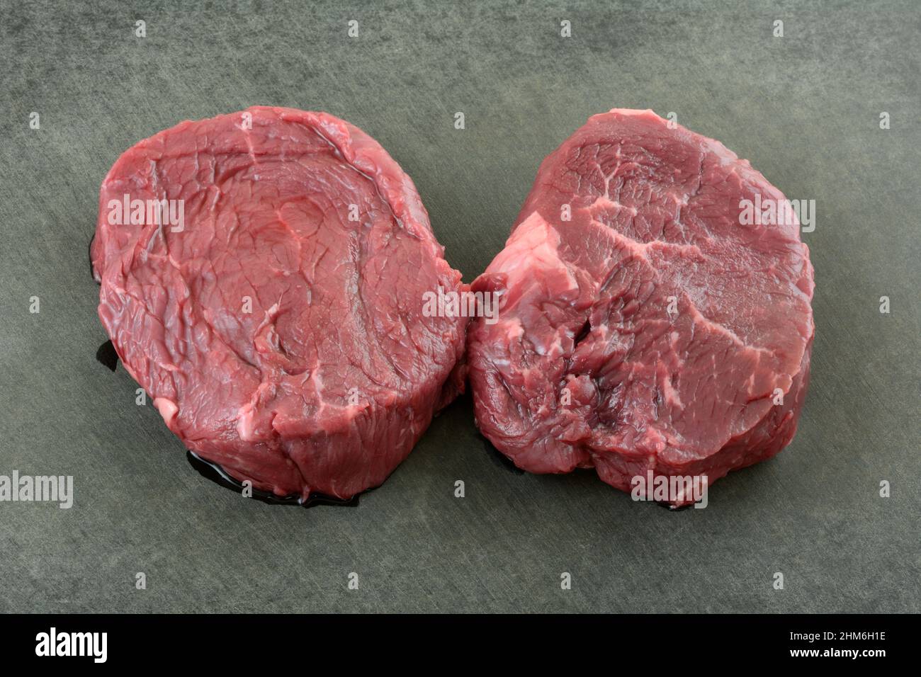 Zwei frische Roh-Rinderfilet-Steaks auf schwarzem Schneidebrett Stockfoto