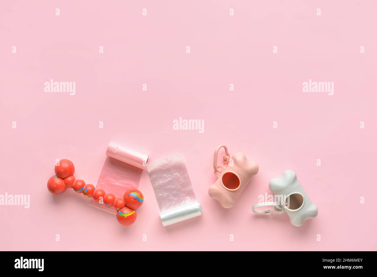 Spender mit PET-Abfalltüten und Spielzeug auf rosa Hintergrund Stockfoto