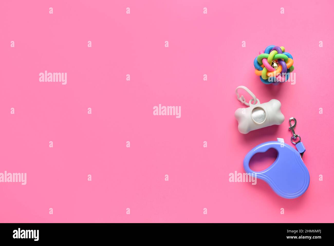 Spender mit PET-Abfalltüten, Spielzeug und Leine auf rosa Hintergrund Stockfoto