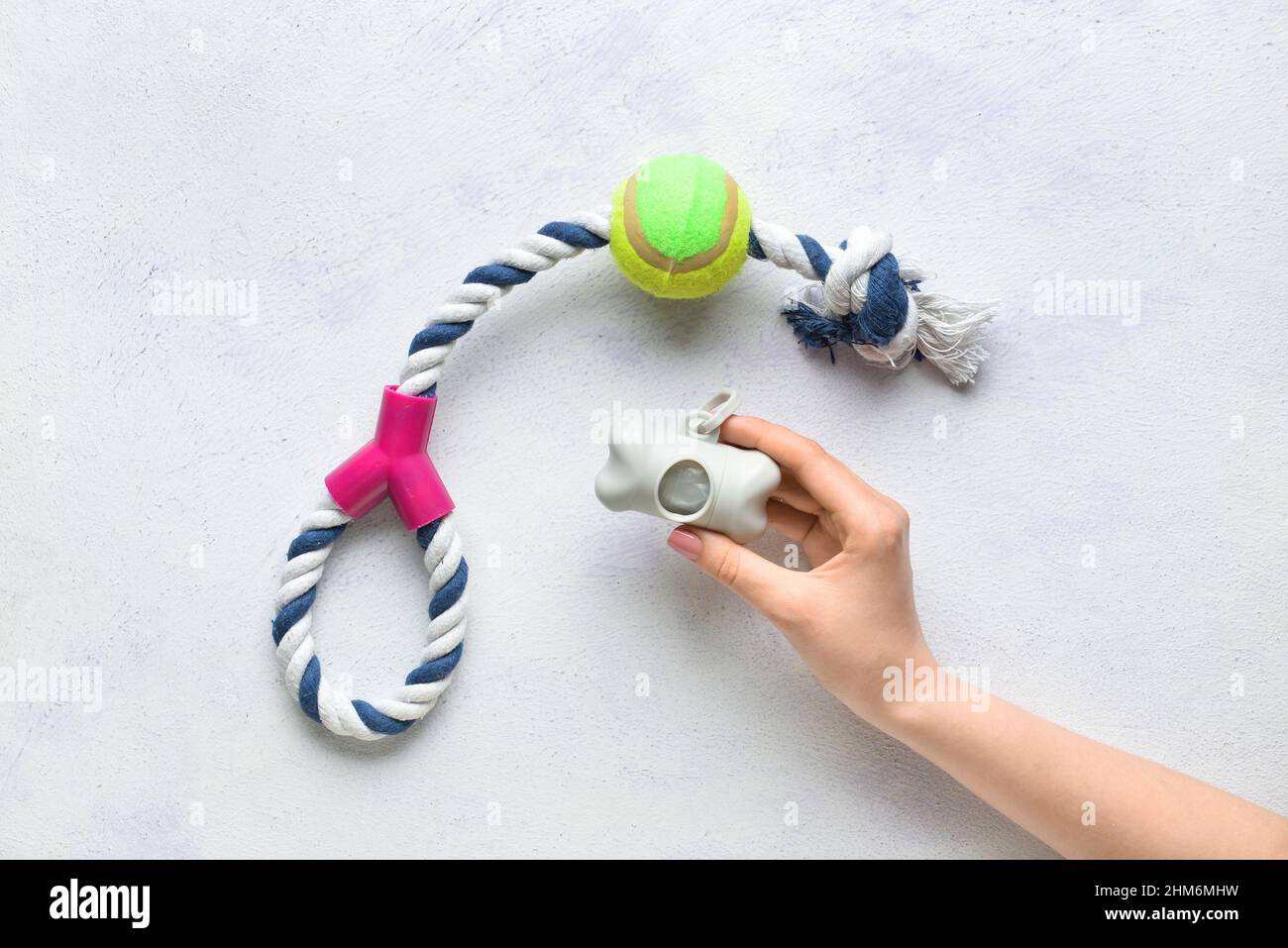 Weibliche Hand mit Haustier Abfallbeutel und Spielzeug auf hellem Hintergrund, Nahaufnahme Stockfoto