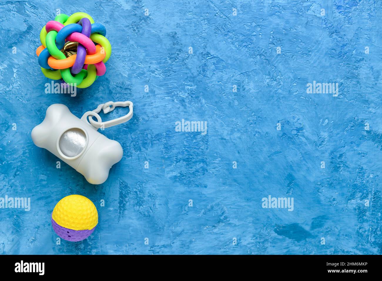 Spender mit PET-Abfalltüten und Gummikugeln auf blauem Hintergrund Stockfoto