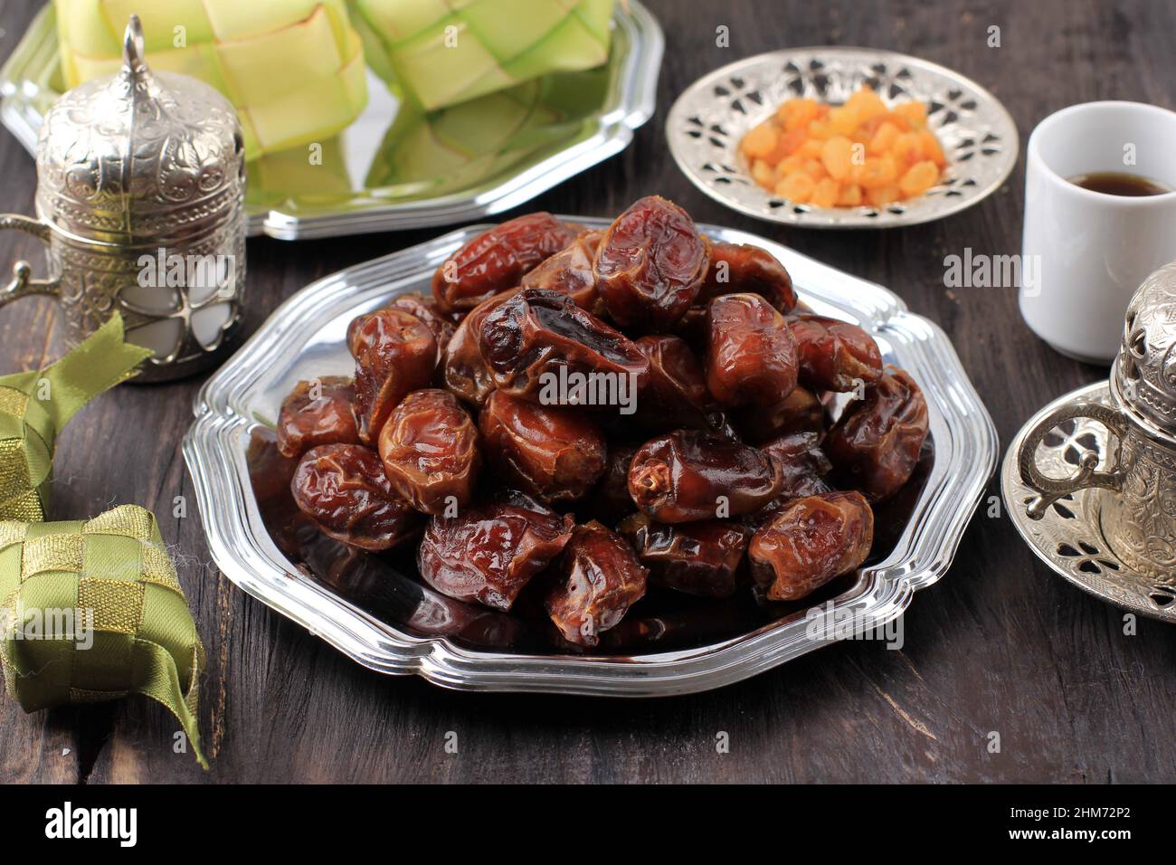 Date Früchte oder Kurma in Silver Dish und auf Holztisch Hintergrund. Dates und Ketupat ist Ramadan-Mahlzeit. Ramazan Iftar-Essen. Stockfoto