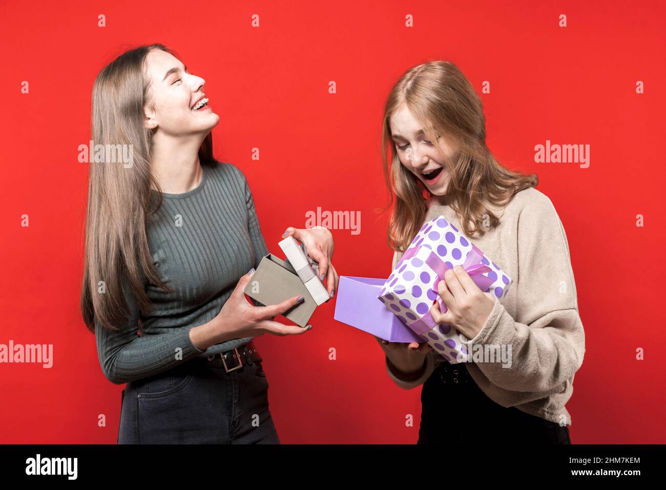 Entzückende Mädchen tauschen Geschenkboxen aus. Zwei niedliche schöne Freundinnen schenken einander Geschenke. Geschenke zum neuen Jahr. Weihnachten. Schwestern. Freunde. Geburtstag. Stockfoto