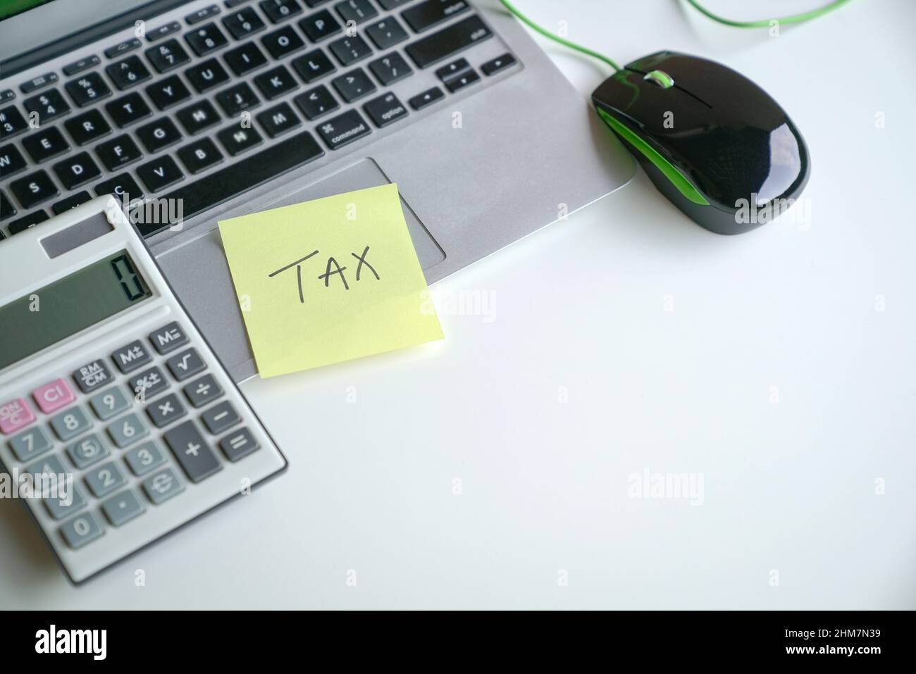 Das Wort Steuer auf gelbem Klebepapier auf dem Laptop und neben dem Rechner. Konzept der Steueranmeldung. Stockfoto