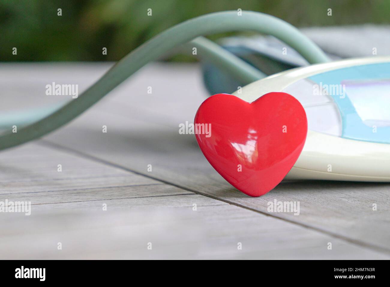 Rote Herzform neben dem digitalen Blutdruckmessgerät. Gesundheits- und medizinisches Konzept. Stockfoto