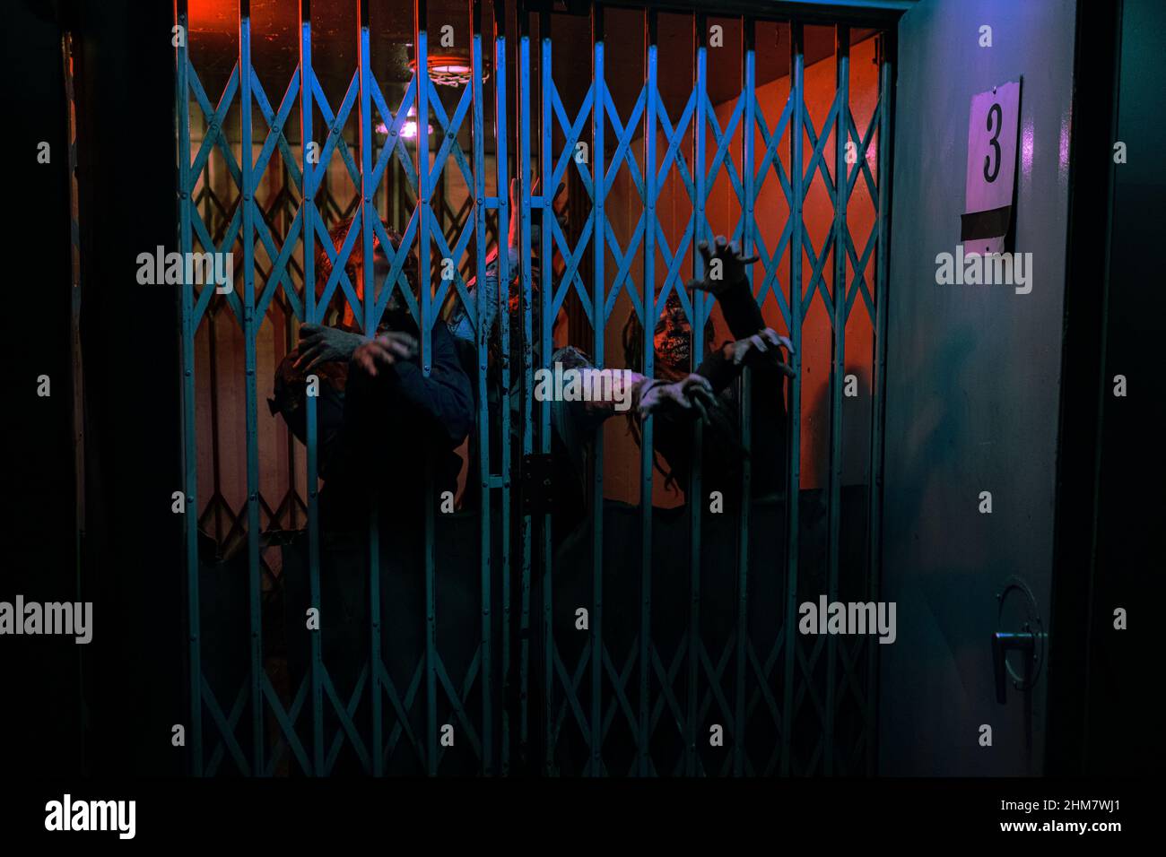 Hintergrundbild von Zombie-Hände, die durch die Tür in dunklen Flur durch rotes Licht beleuchtet, kopieren Raum Stockfoto
