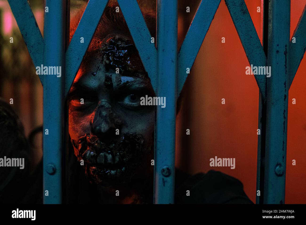 Nahaufnahme von Zombie Gesicht in Gore FX Make-up Blick auf die Kamera durch die Tür in dunklen Flur gefangen, kopieren Raum Stockfoto