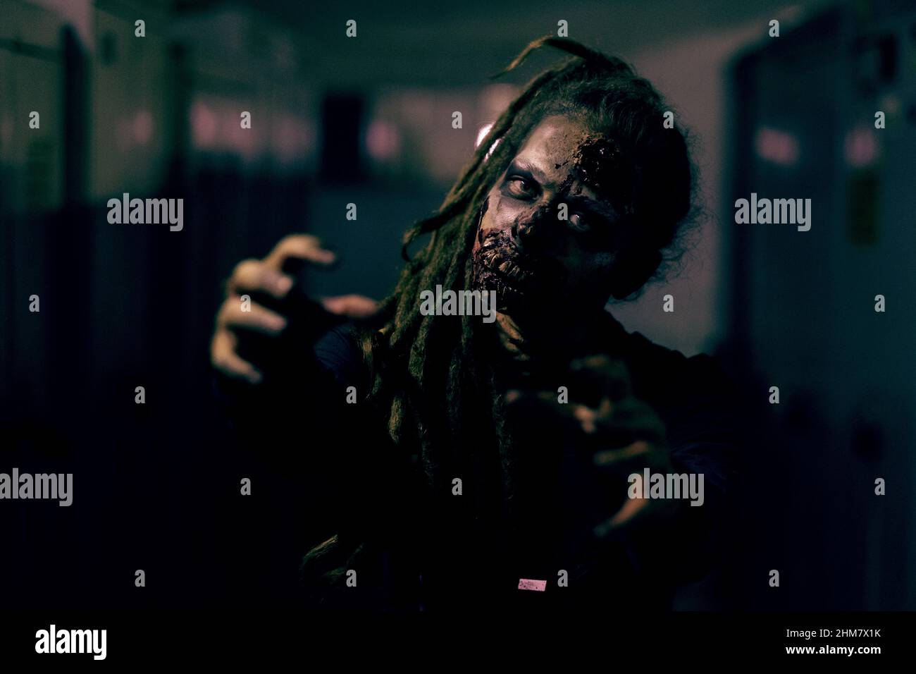 Frontansicht Aufnahme von gruseligen weiblichen Zombie Blick auf die Kamera und die Reichweite in dunklen Raum Stockfoto