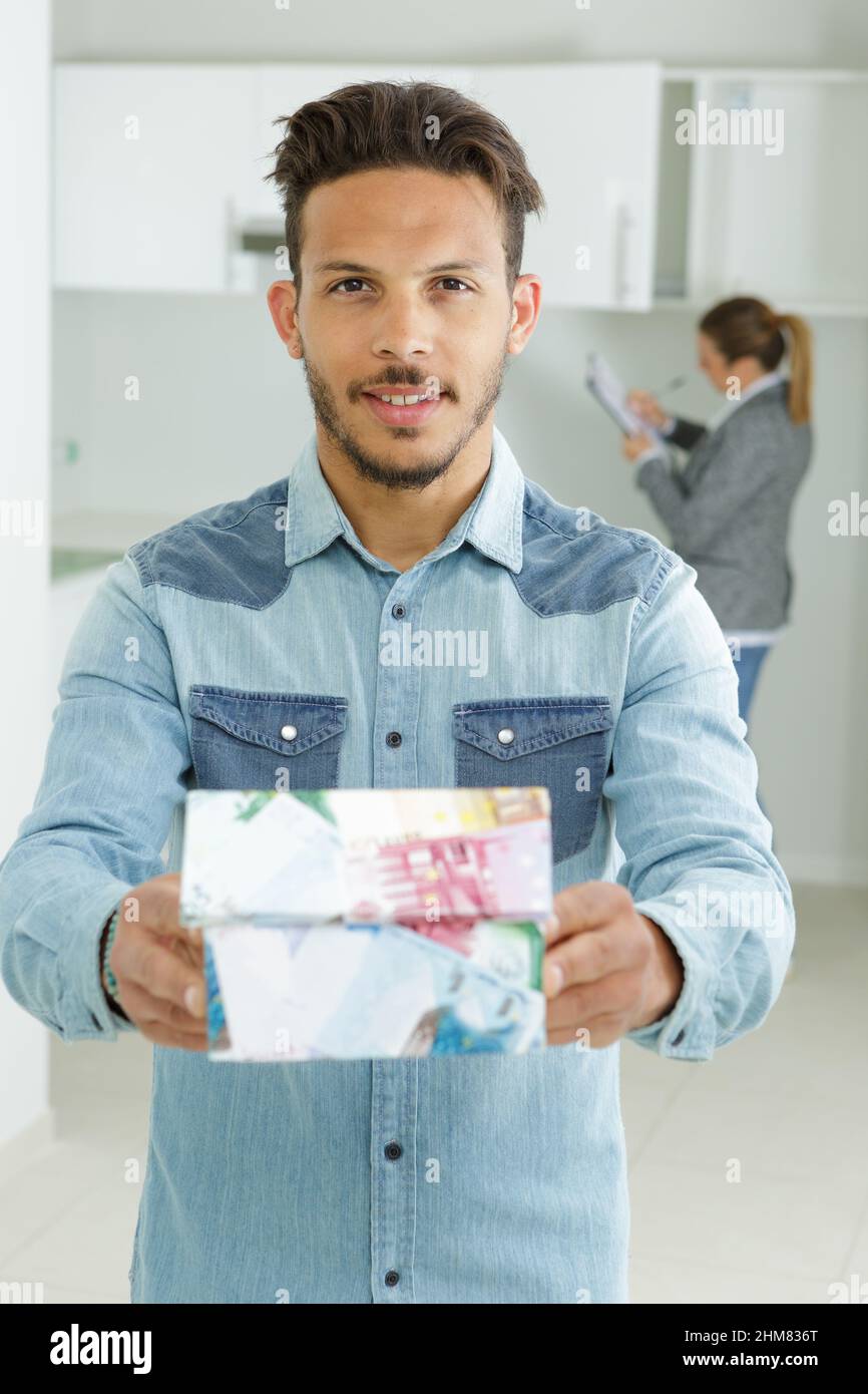 Junger Mann mit einem Modellhaus aus Banknoten Stockfoto