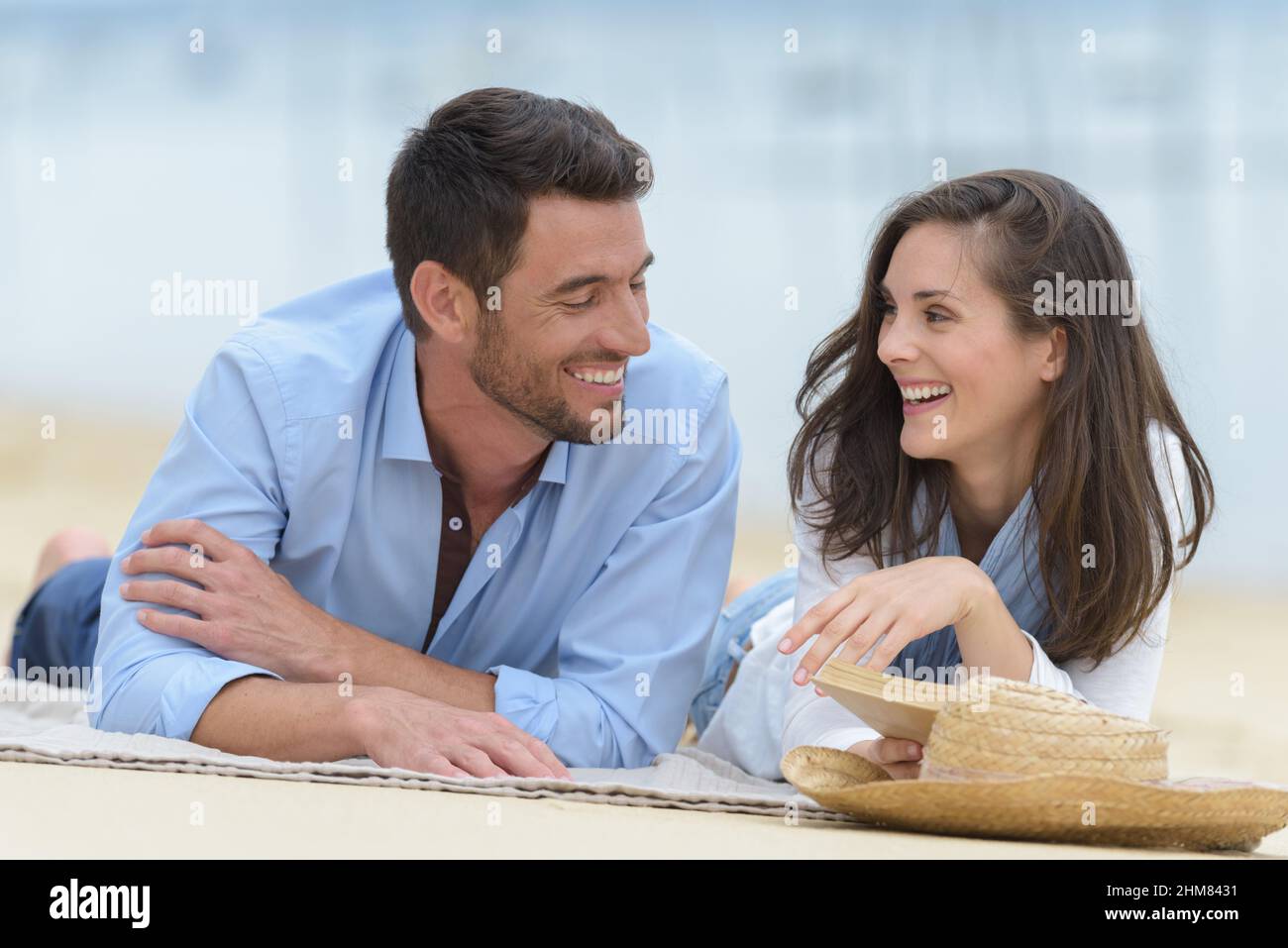 Paar auf legerer Kleidung, die auf der Strandmatte liegt Stockfoto