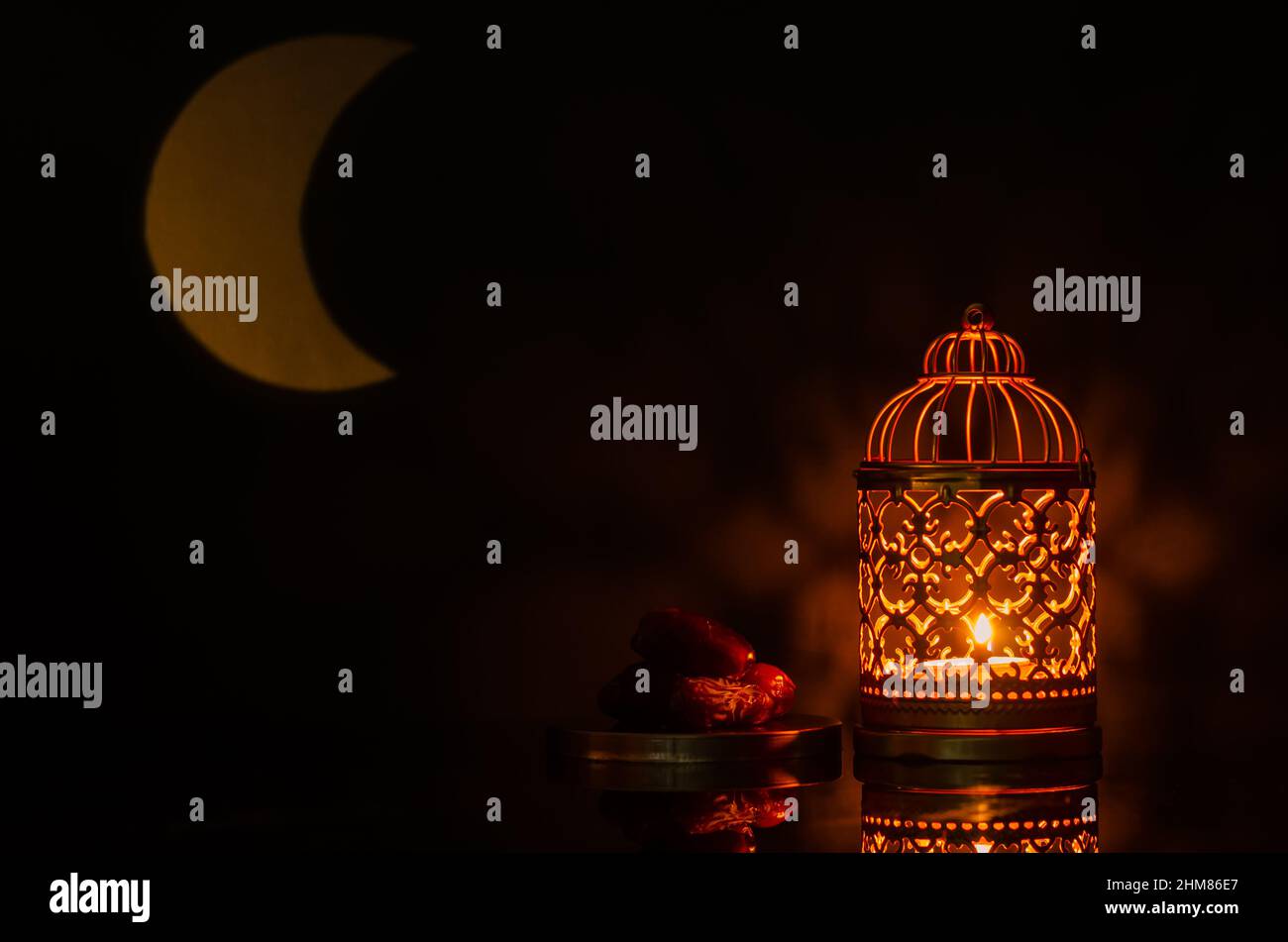 Selektiver Fokus von Laterne und kleinen Teller mit Datteln Frucht mit Mondform aus Licht auf Hintergrund für das muslimische Fest des heiligen Monats Ramadan K Stockfoto