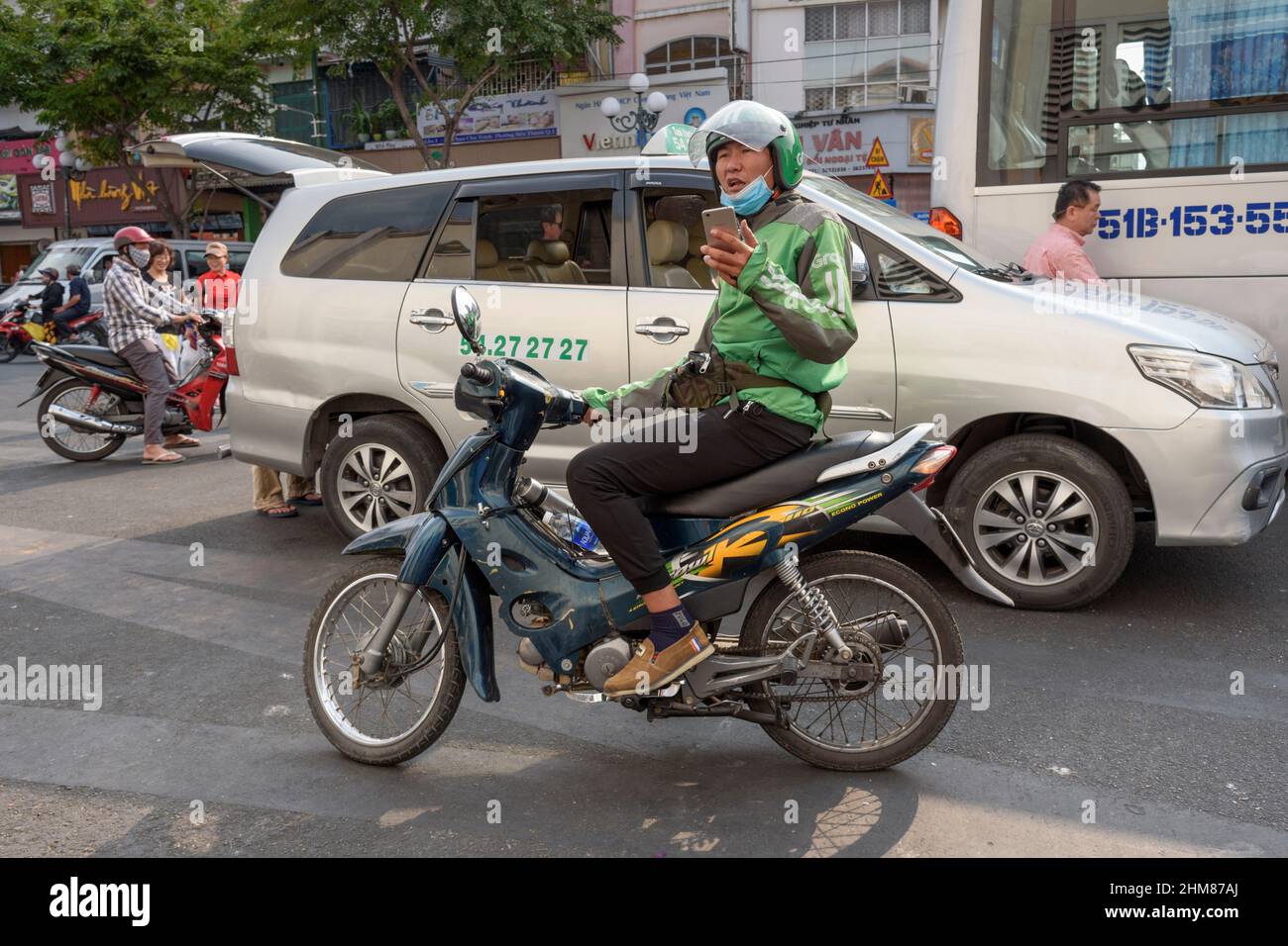 Auf den Straßen von Ho-Chi-Minh-Stadt (Saigon), Südvietnam und Südostasien wartet ein Fahrer von Grab Motorcycle auf Fahrgäste Stockfoto